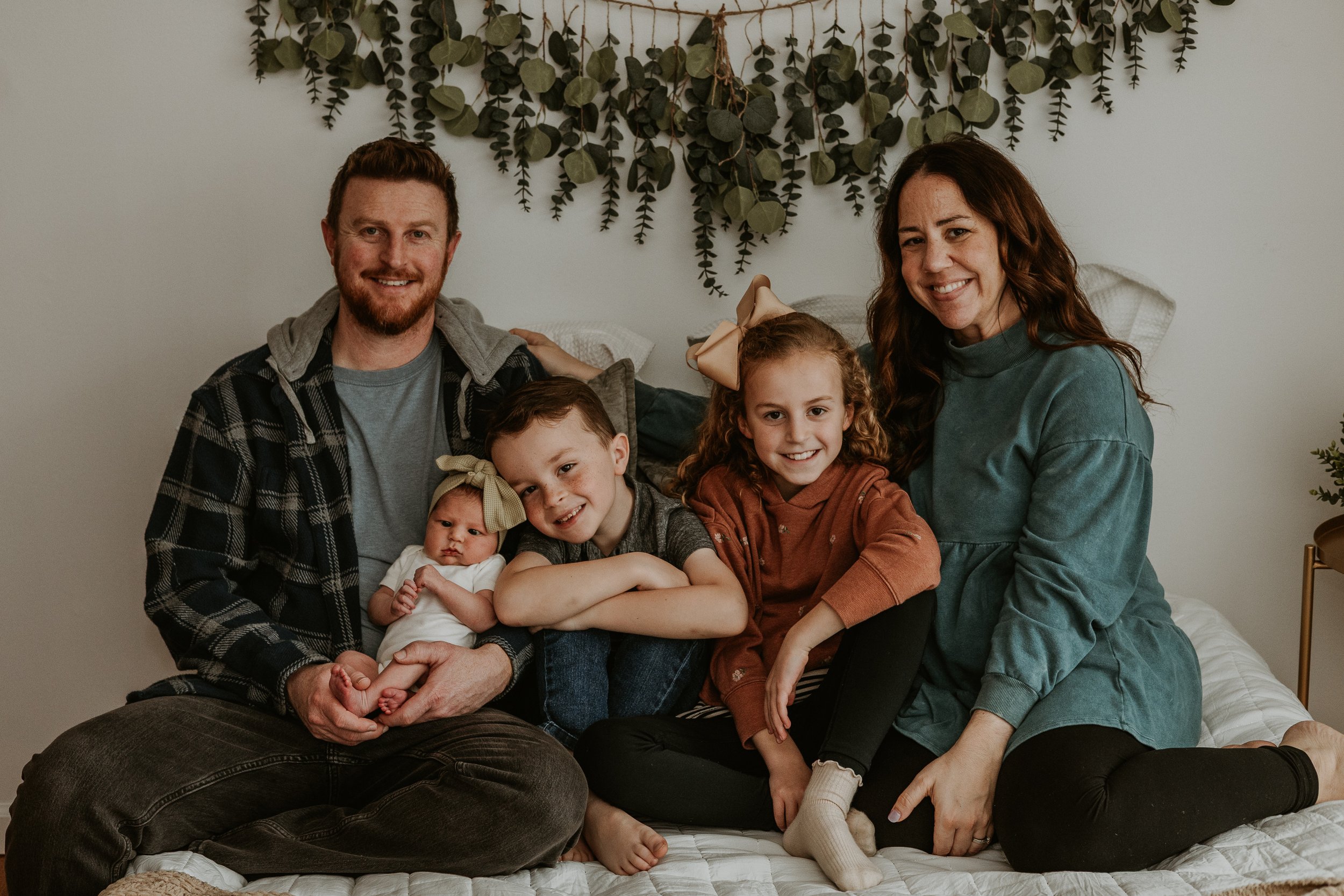 A family smiles sweetly as they enjoy the first week of life with the newest member of their family.