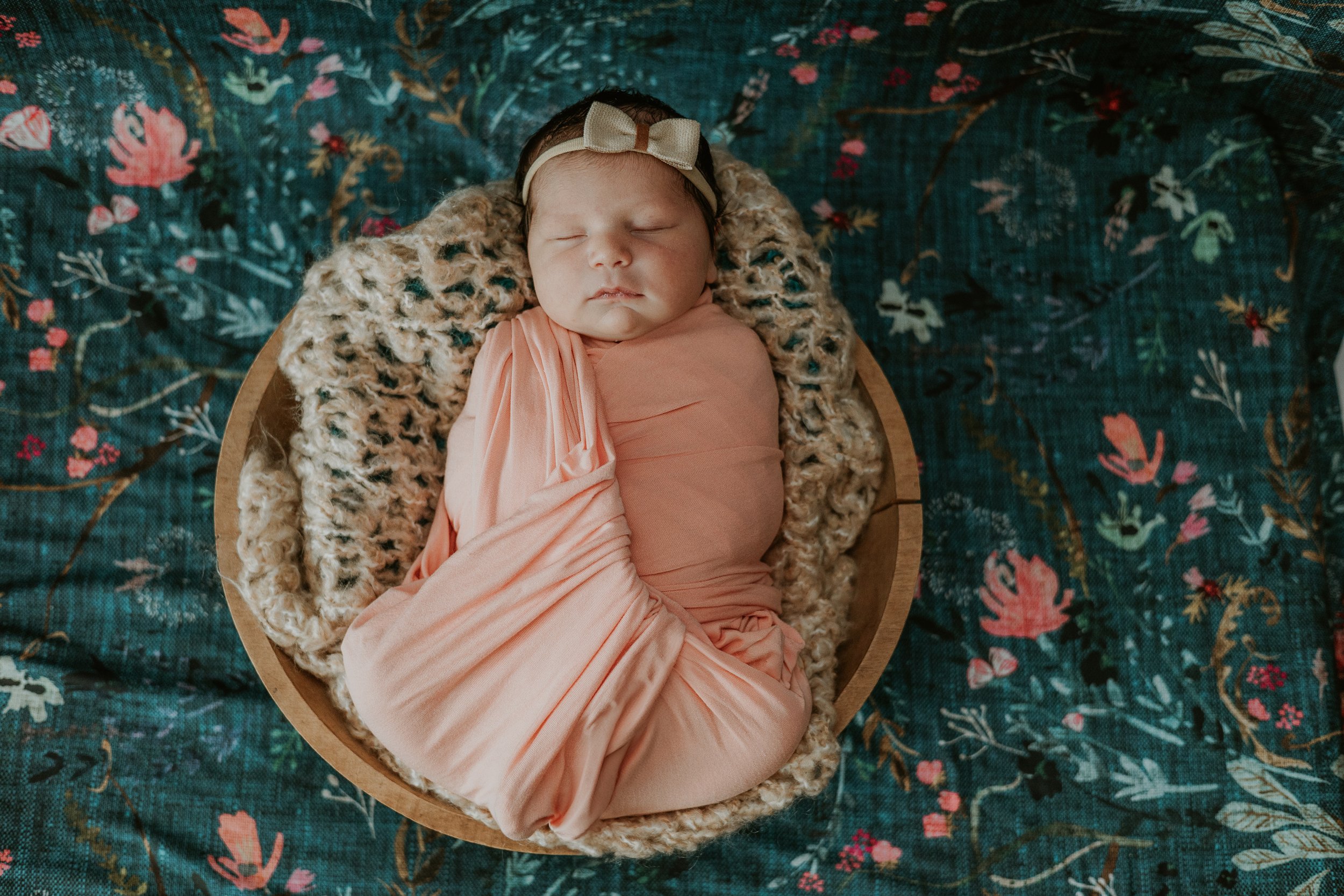 This baby sighs peacefully during her nap, swaddled securely in a wooden bowl.