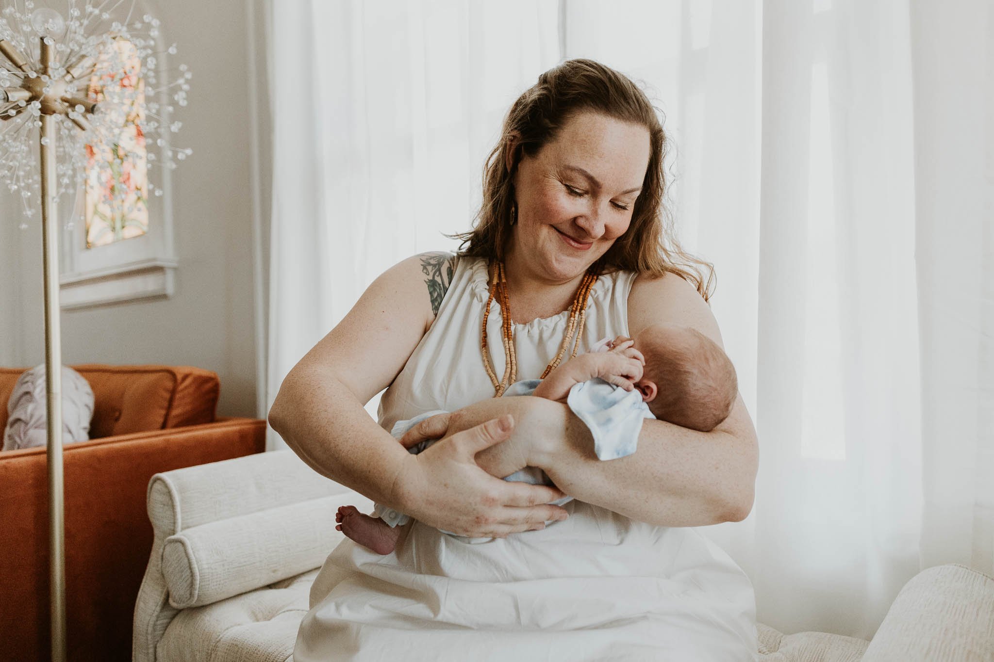 A mother craddles her daughter, looking down and admiring her features while at their newborn photography session in Bloomington, Illinois.