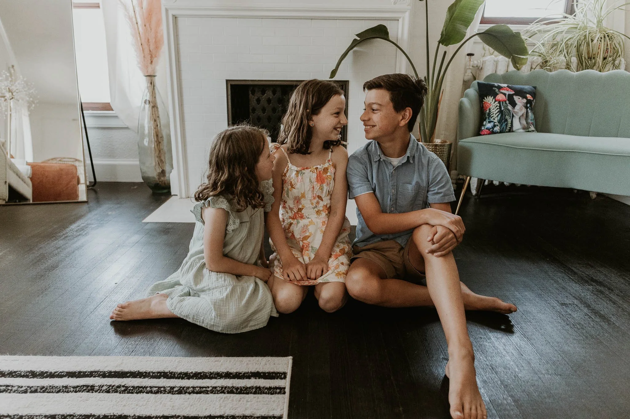 Siblings look at each other with laughter in their eyes while a Bloomington Illinois photographer captures them candidly during a family photoshoot.