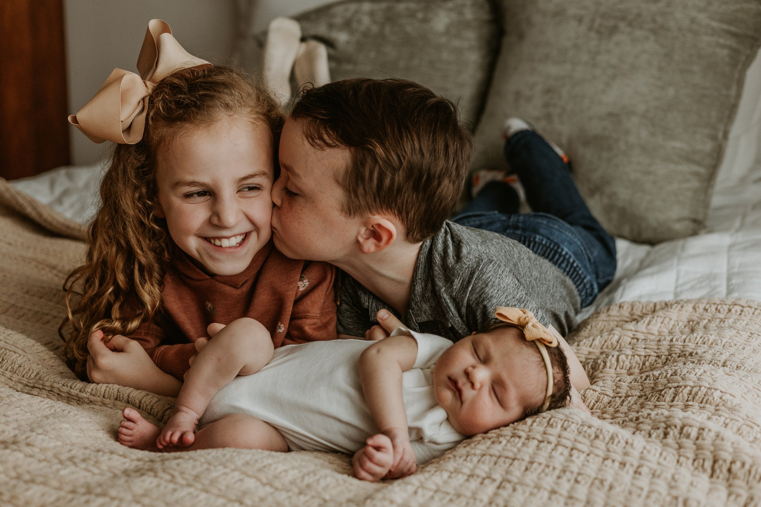 A brother plants a kiss on his big sister's cheek.