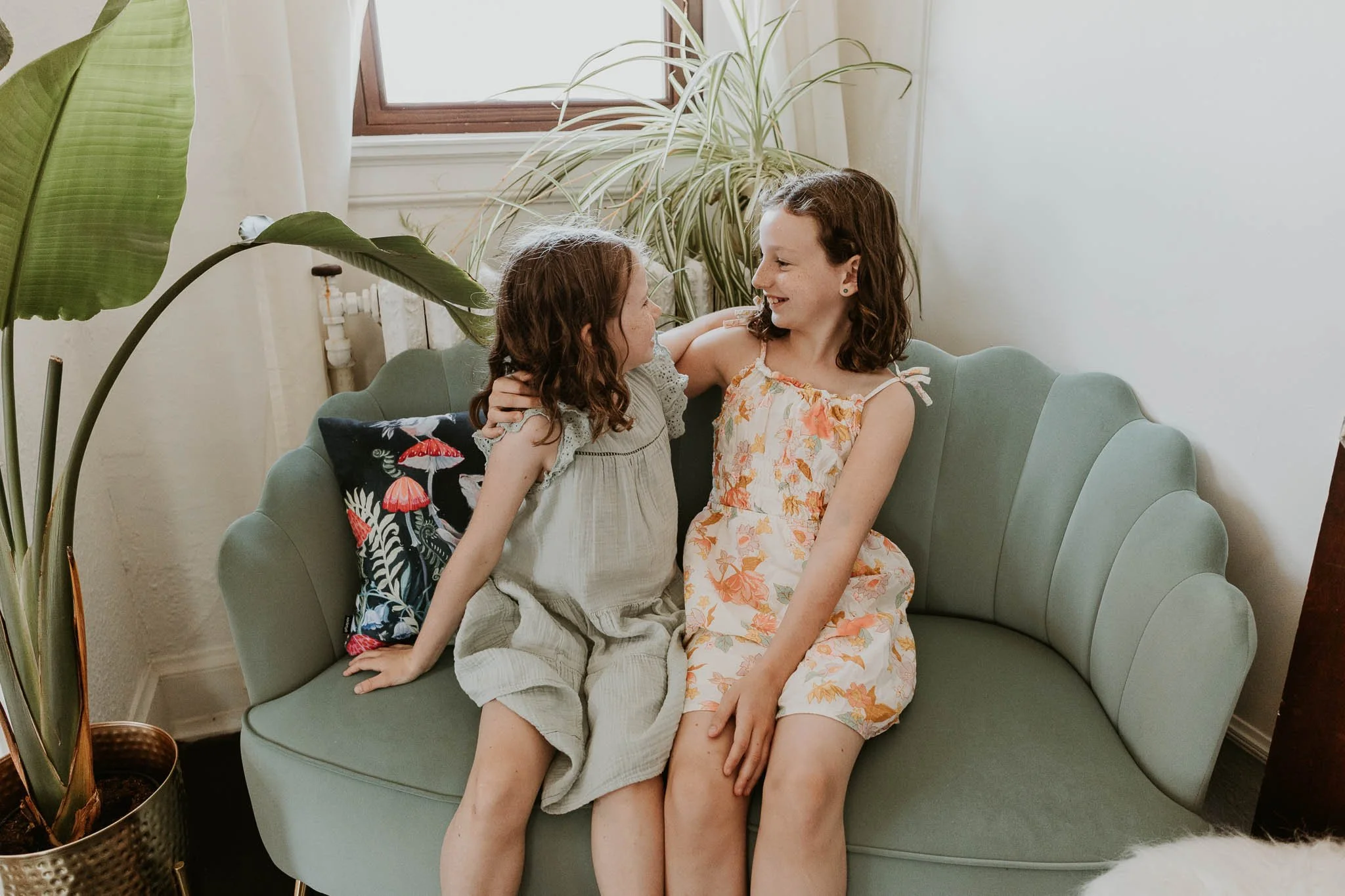 Two sisters smile at each other during a family photoshoot in Bloomington Illinois.