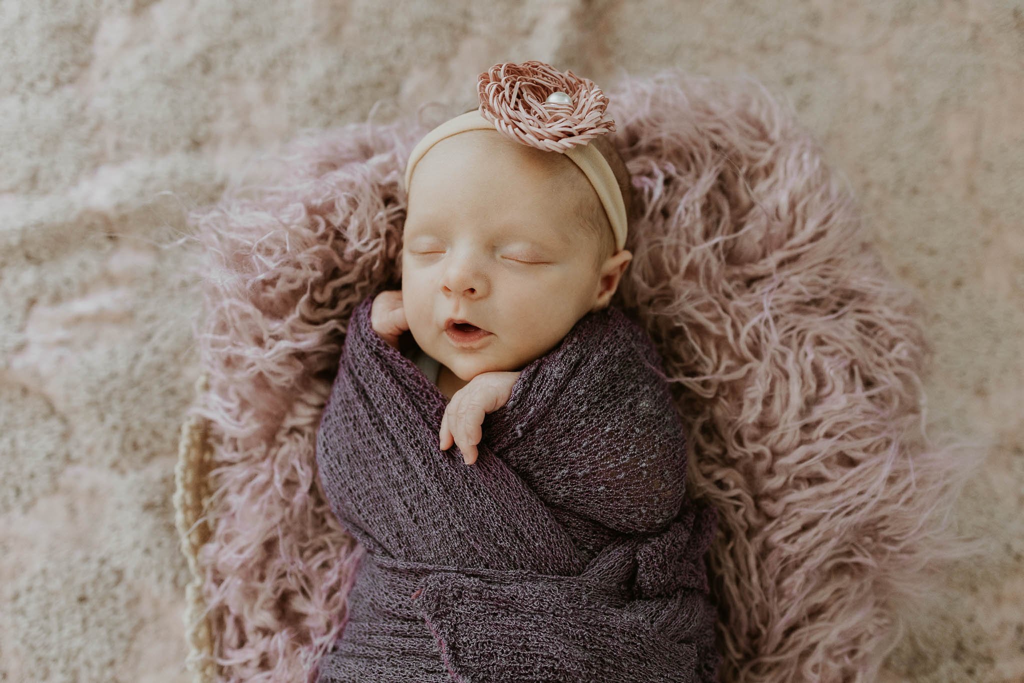 Posed photos for newborn photoshoots can be some of parents' favorite pictures. Baby Ruby is sleeping her her purple muslin swaddle for her close up.