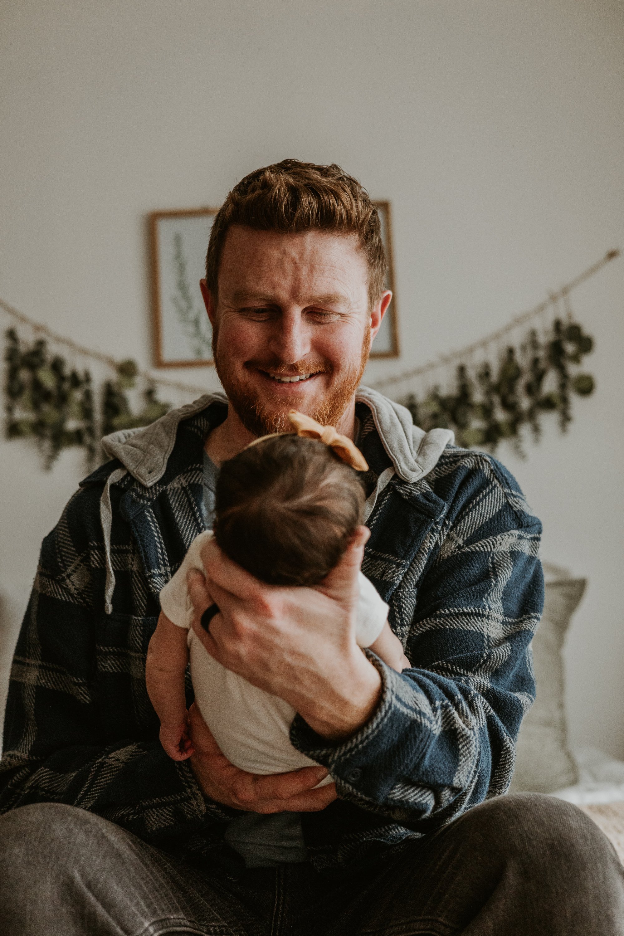 A dad smiles down on his new daughter while she sleeps peacefully in his arms.