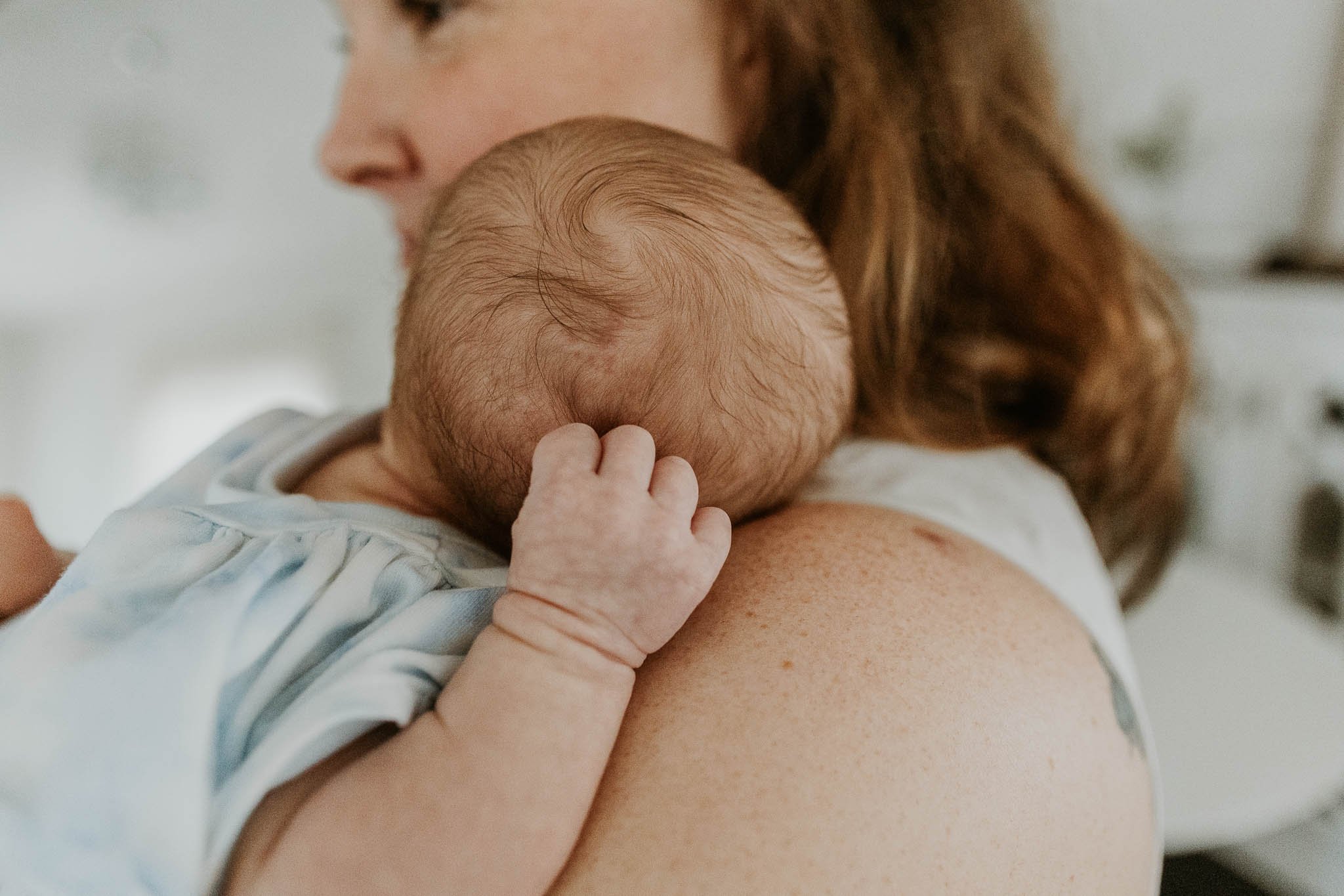 Baby feeling comforted by her mother during a newborn photoshoot.