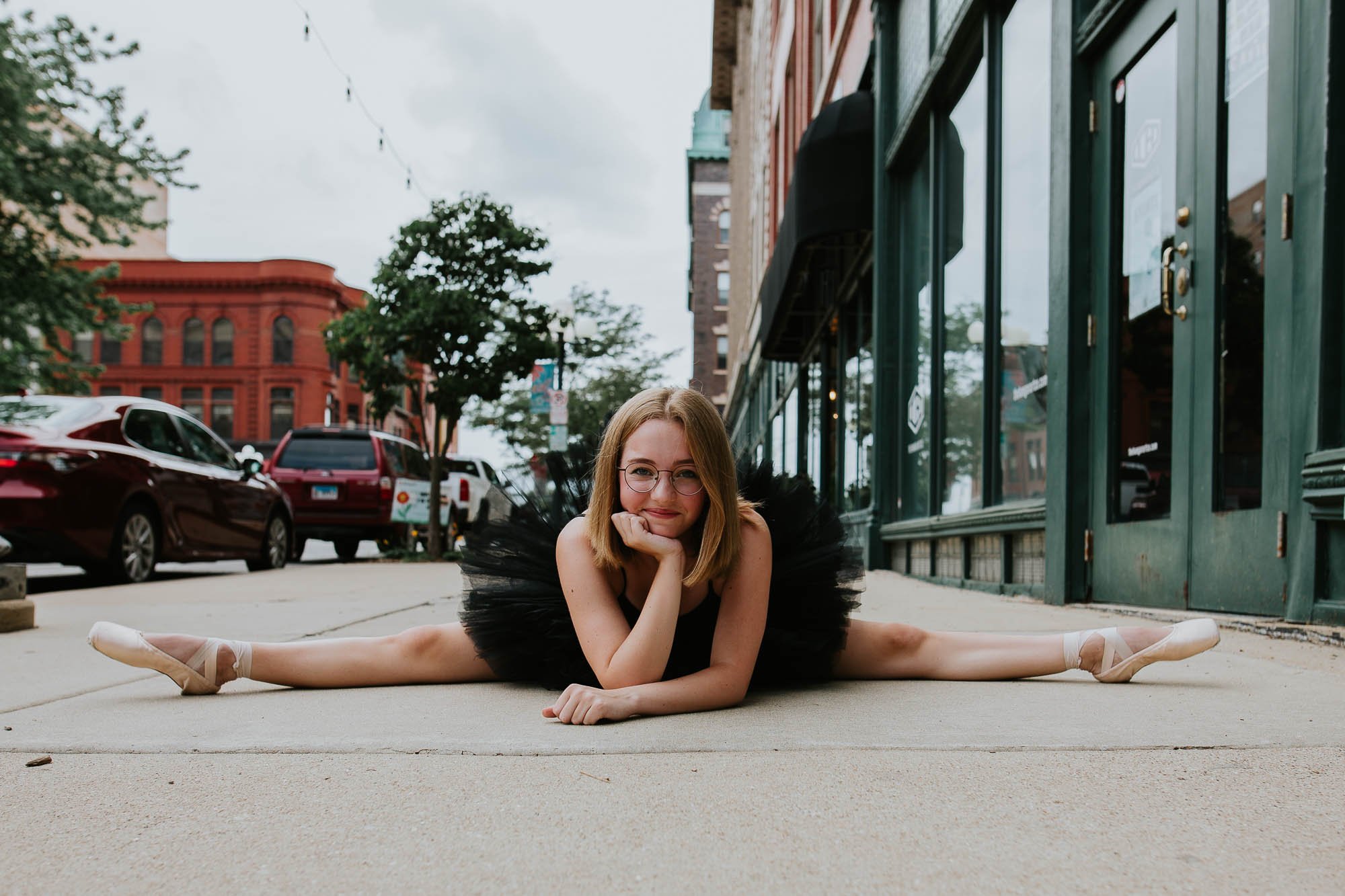 A ballerina holds herself in the splits while smiling at the camera.