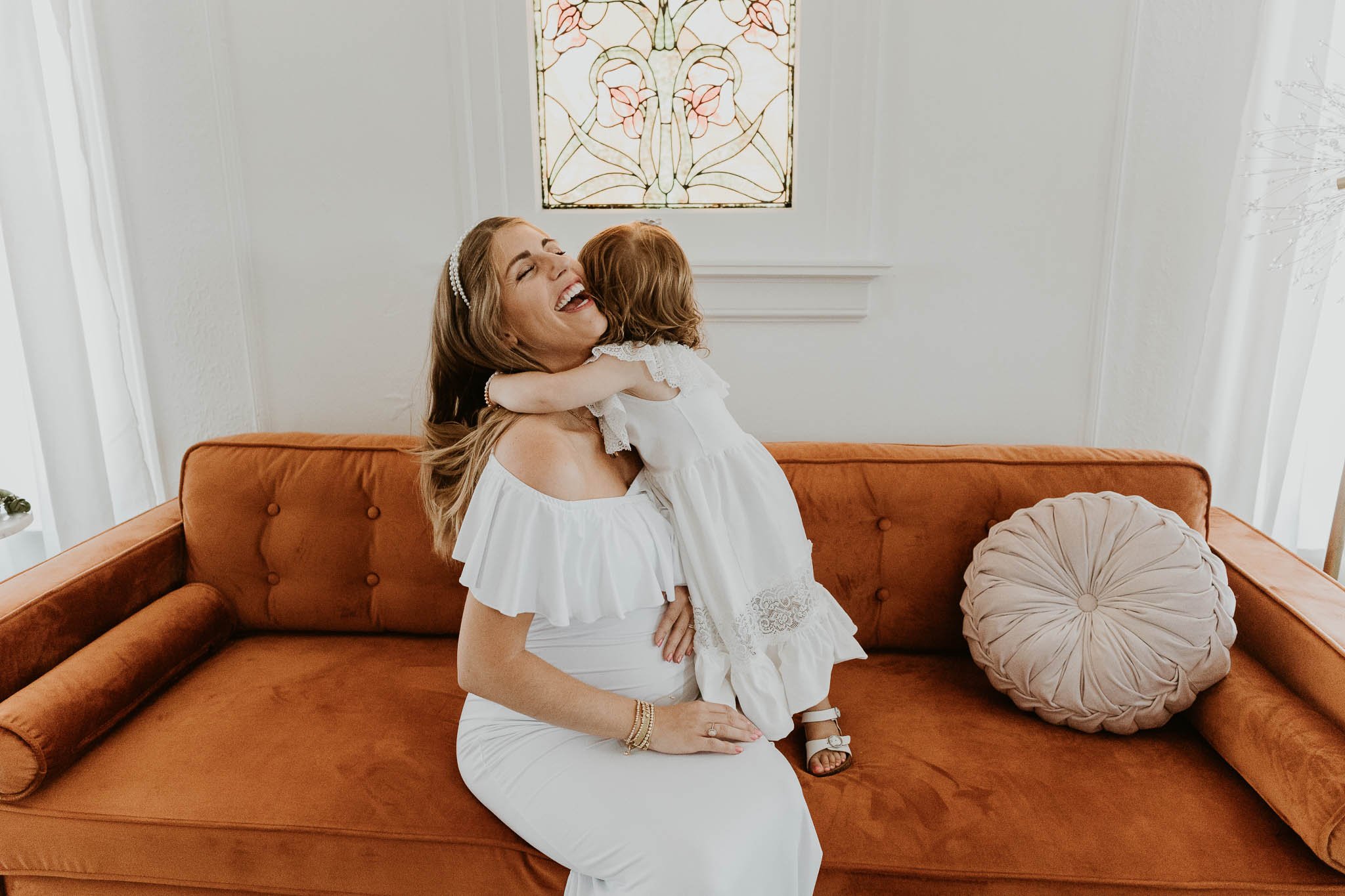 A pregnant mom delights as her 2 year old daughter throws her arms around her neck during her maternity photoshoot in Central Illinois.