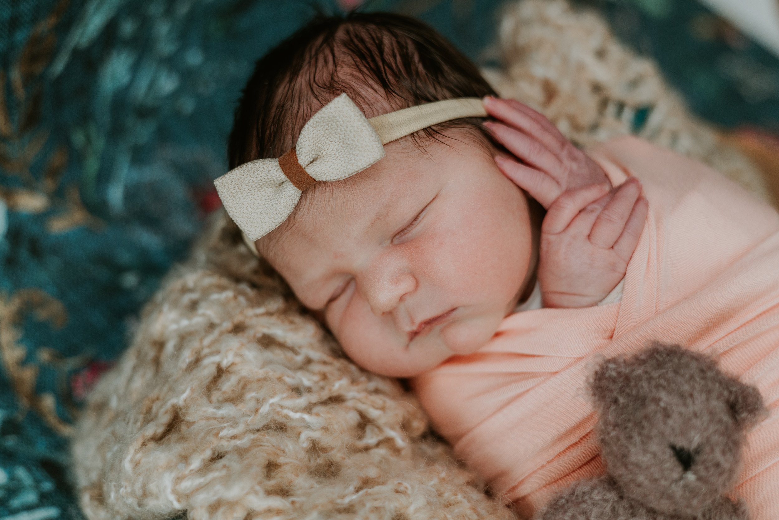 Fingers peek out while a baby naps inside her swaddle, resting calmly during her newborn photoshoot.