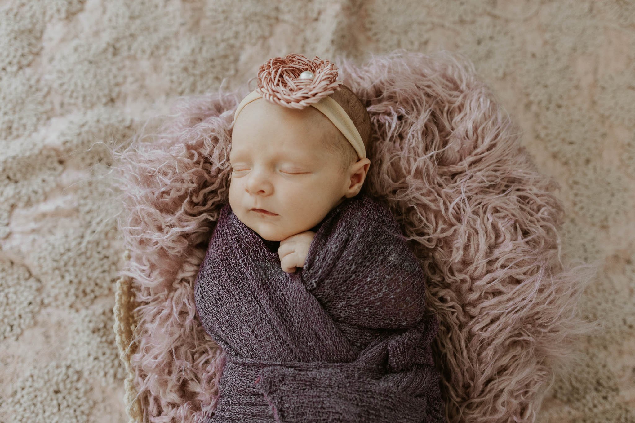 Professional photographers pose babies, like Ruby, for newborn photoshoots with swaddles, backdrops, and floor drops.