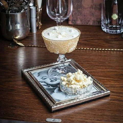 An exotic cocktail design inspired by Marilyn Monroe on a tray, on a wooden table.