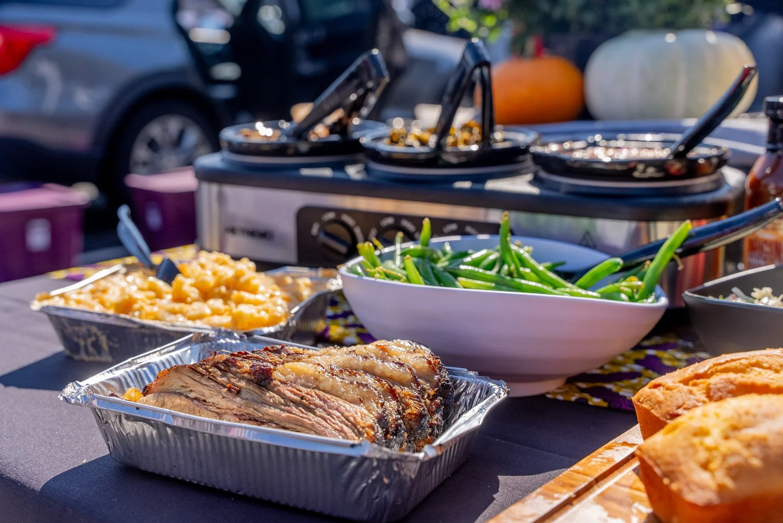 Holiday catering spread: sliced beef brisket, baked macaroni and cheese, green beans and cornbread in serving pans