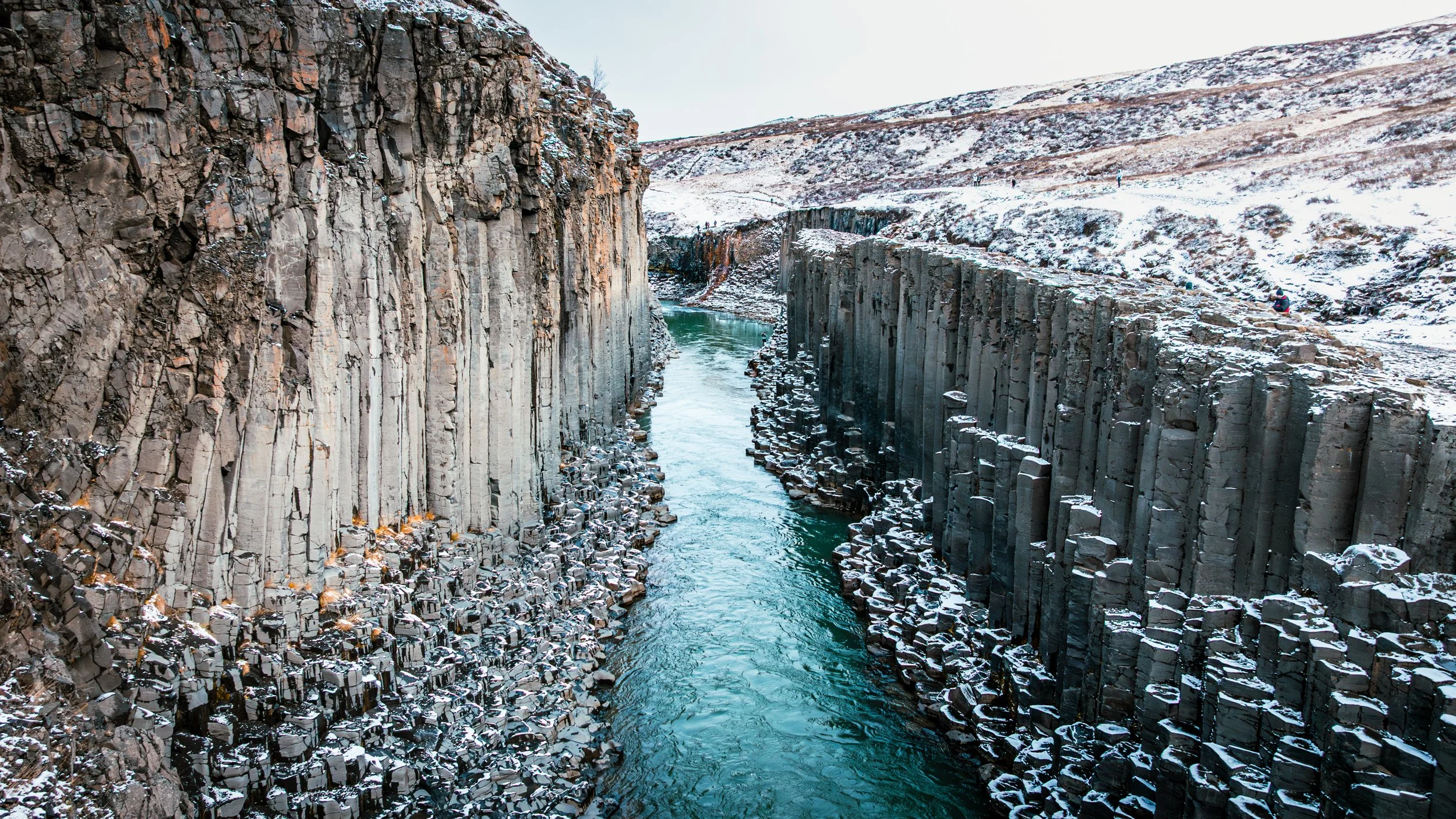 Aerial drone view of Stuðlagil Canyon in Iceland during winter, showing hexagonal basalt columns and turquoise river