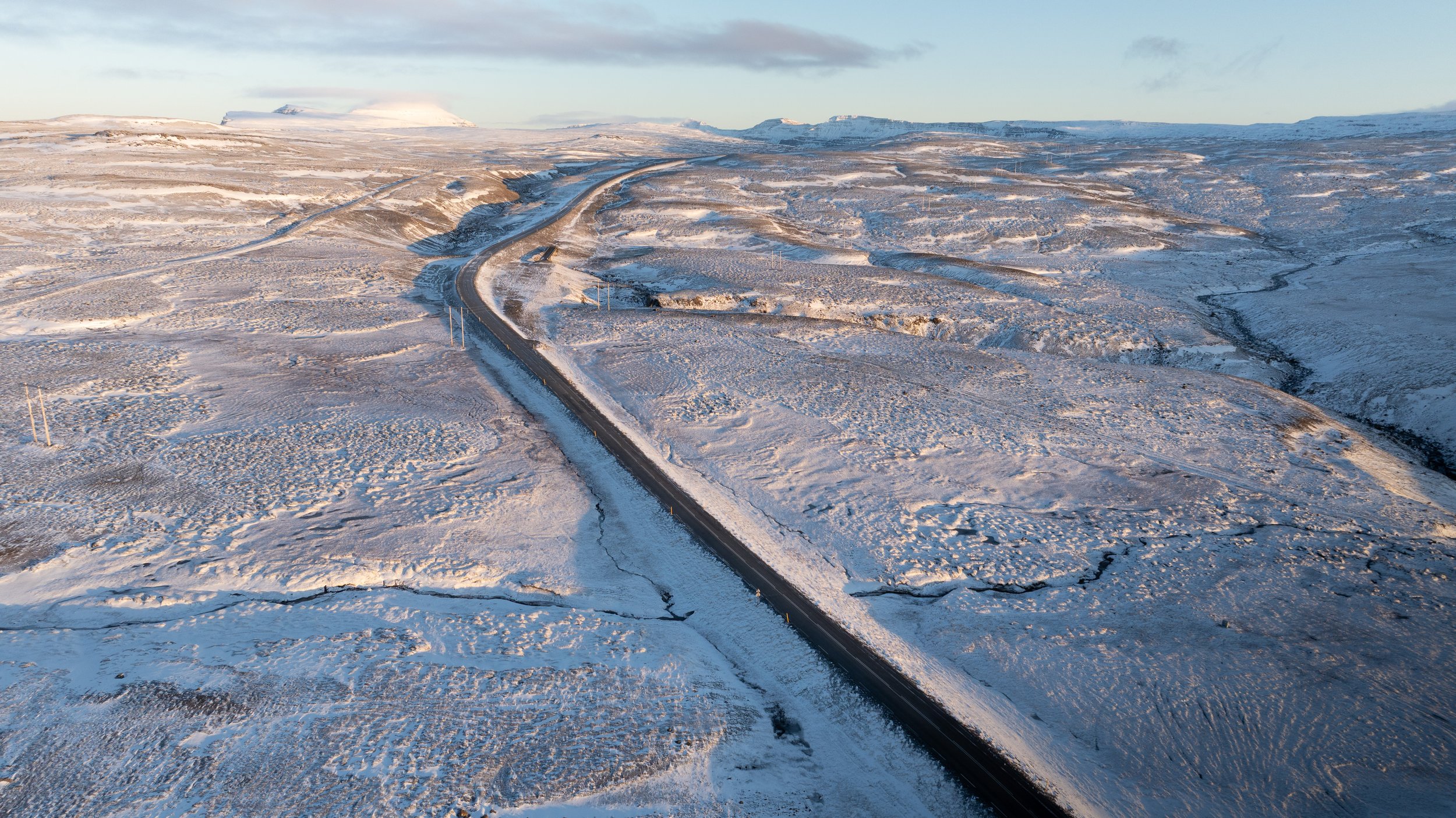 Drone view of icy road in Iceland surrounded by snow