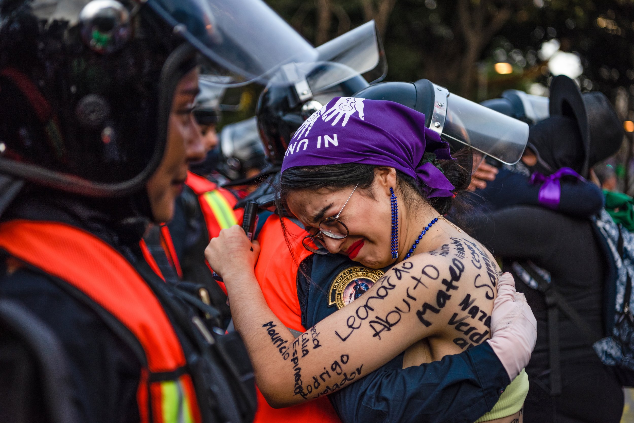  A woman embraces a female police officer at the 2022 International Women’s March in Mexico City. Wearing a purple scarf symbolizing solidarity with the marchers, the officer nodded in agreement as the activist called justice for the thousands of wom