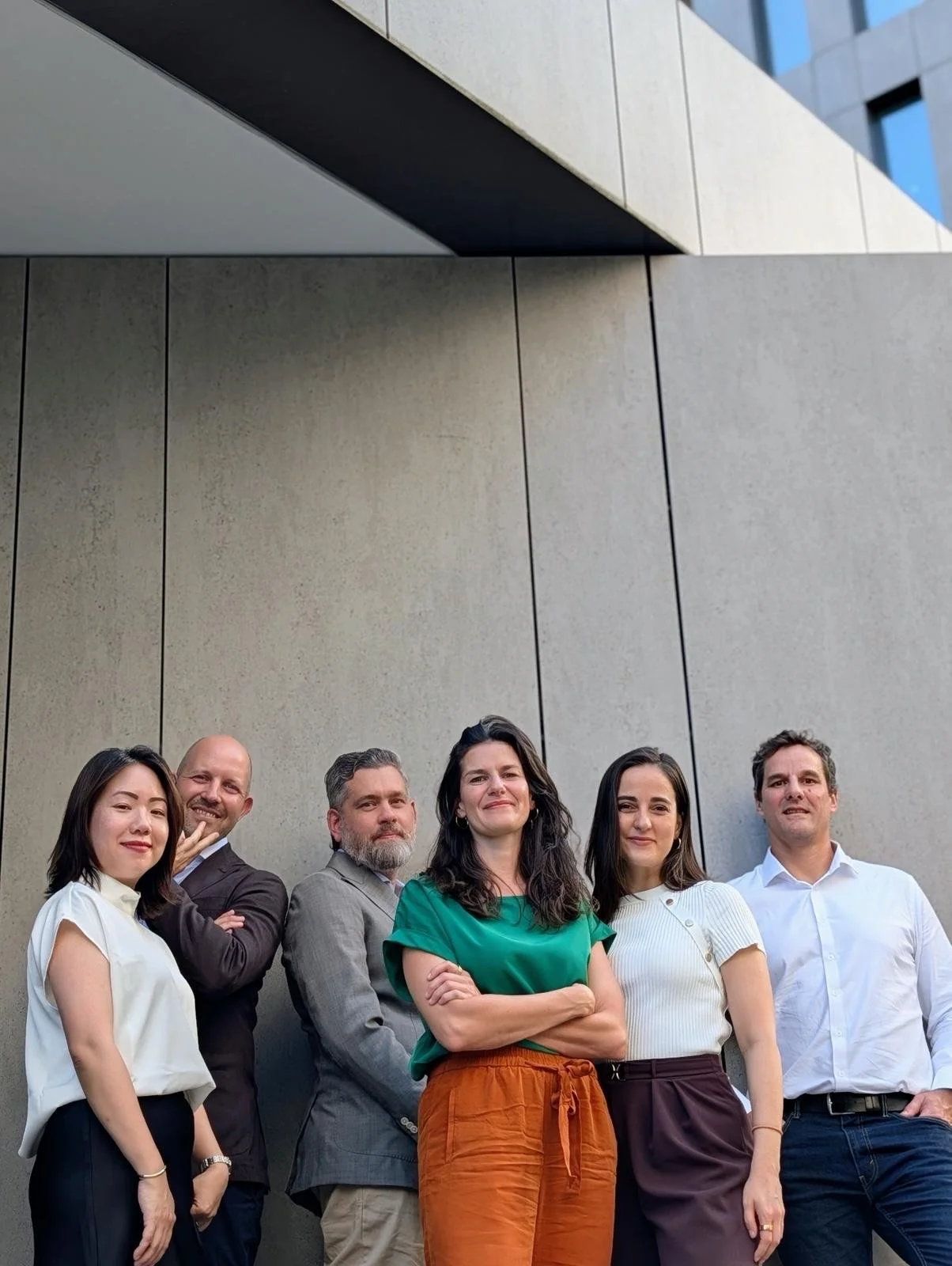The Meliodays team standing together in front of the office building, smiling at the camera.