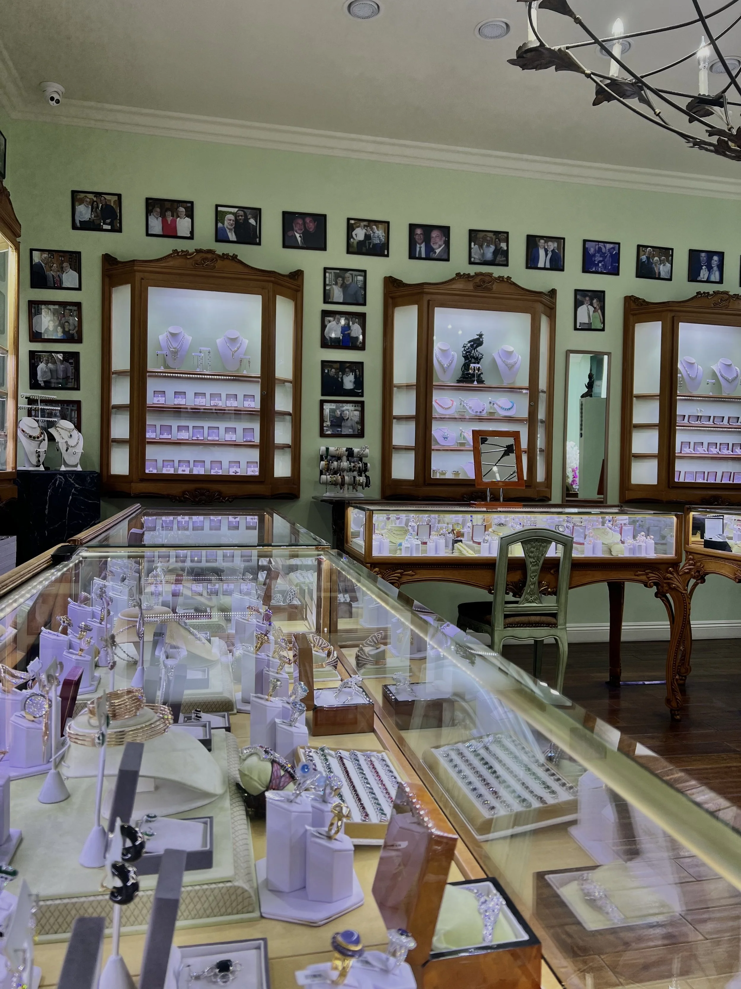 Jewelry store display with glass cases filled with rings, necklaces, and bracelets, and framed photographs on the wall.