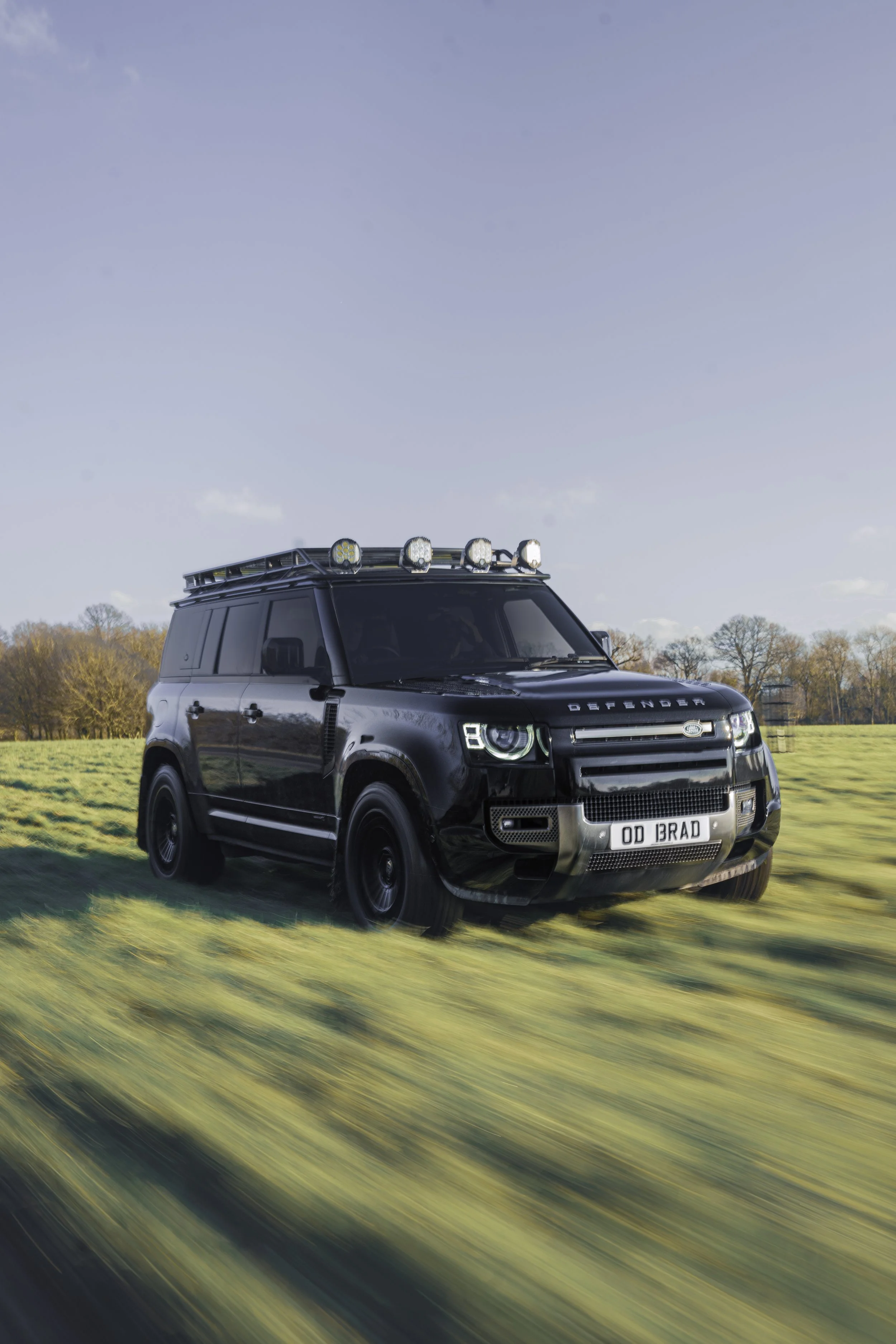  Front view - new generation defender driving at speed across grass