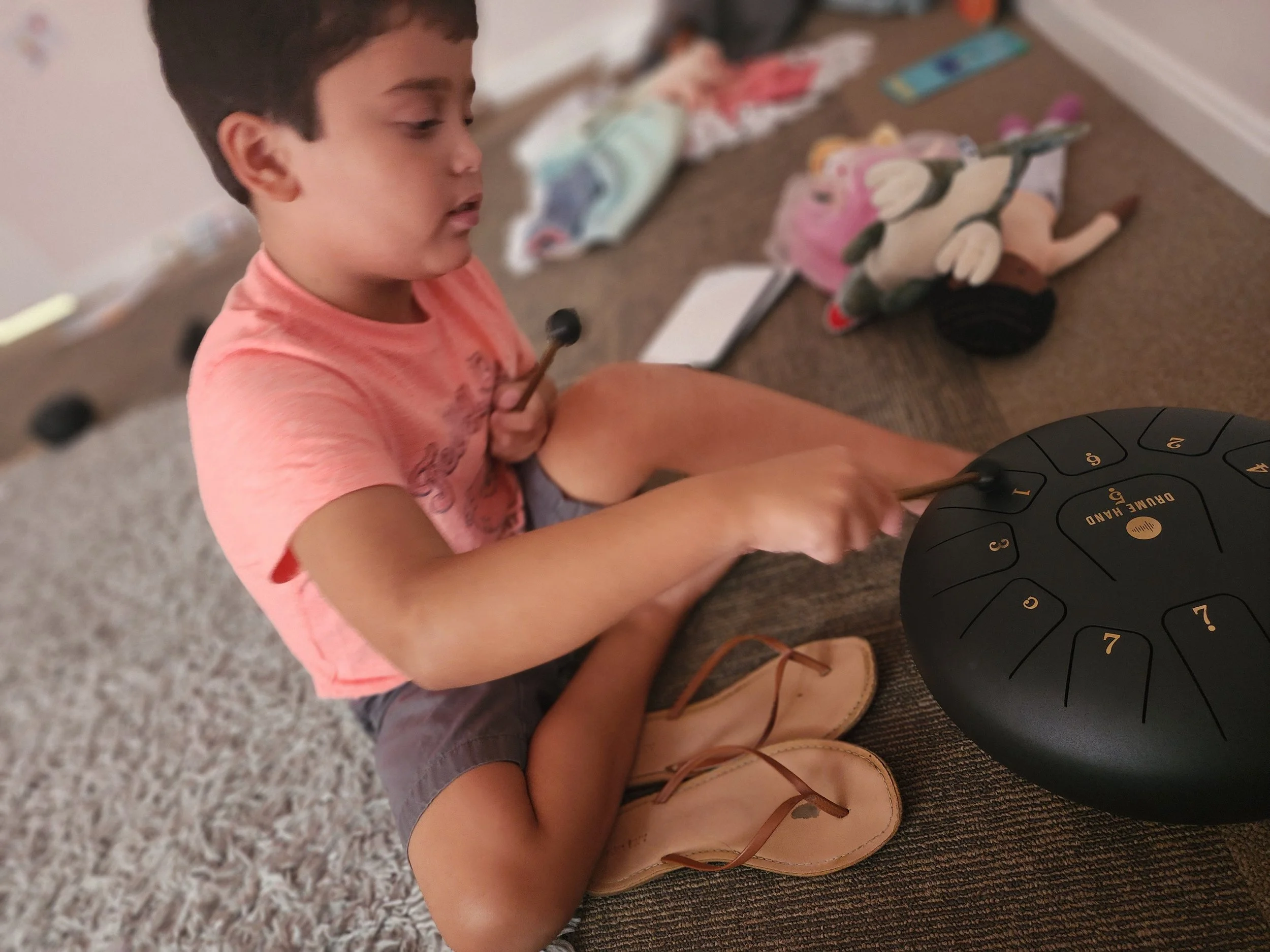Young child exploring a steel tongue drum during a music therapy session at The Sonatina Center
