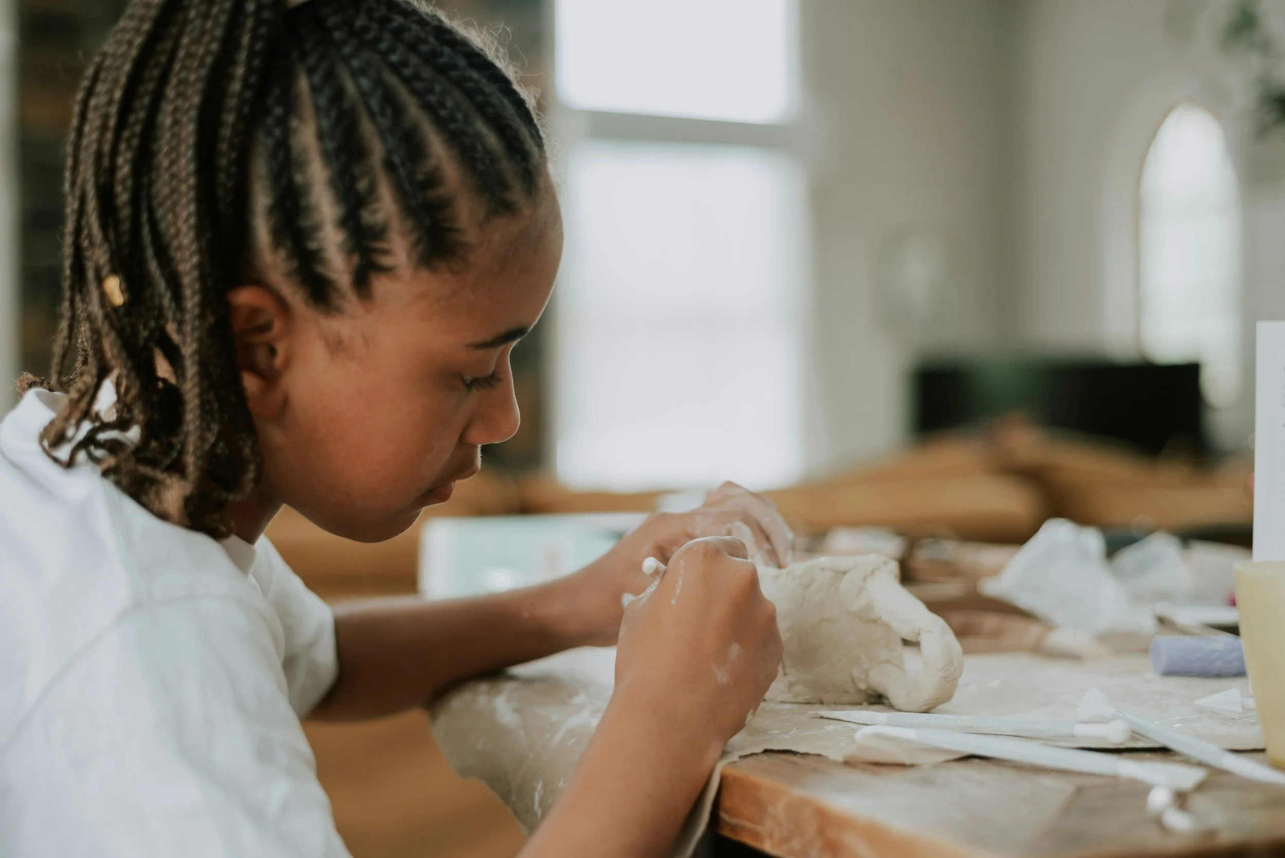 Young girl focused on sculpting clay at a table during an art therapy session for anxiety