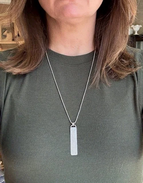 Model wearing Artisan Botanica Collection pendant by KFinn Designs, elongated sterling silver pendant with textured botanical etching