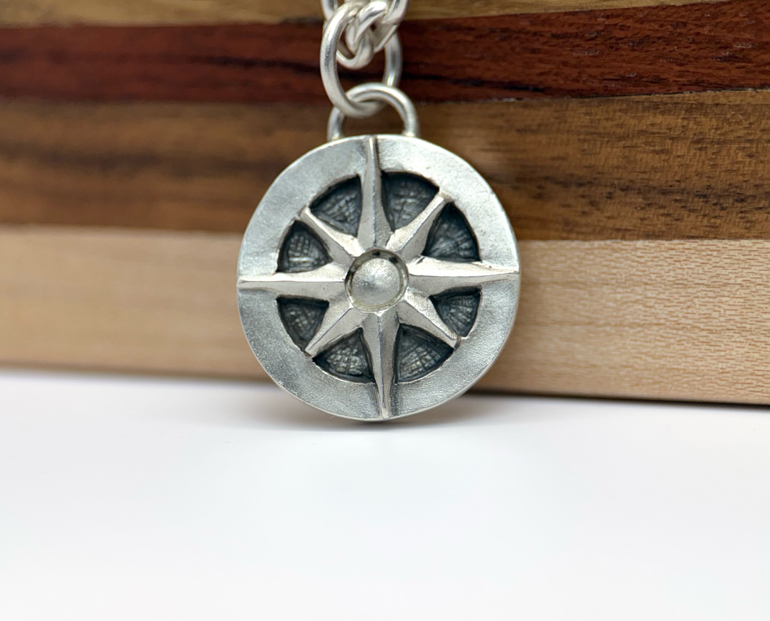Close-up of The Wayfinder Pendant by KFinn Designs, handcrafted sterling silver compass rose pendant with oxidized finish on a sterling silver oval rolo chain.