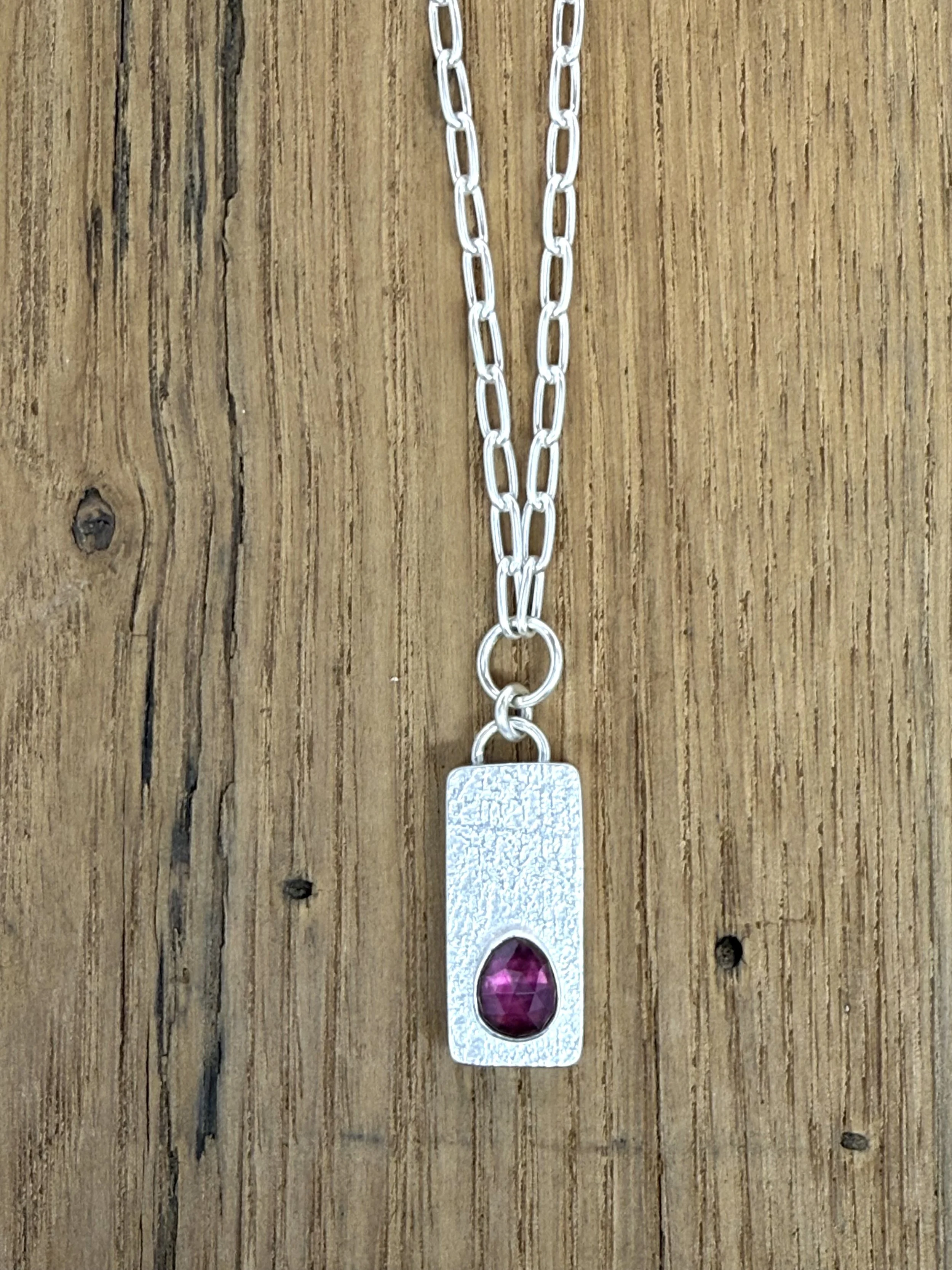 Keystone-Pendant-kfinndesigns-rhodolite-garnet-lying-flat-on-wood-close-up.jpg