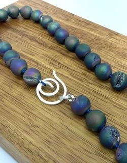 Close-up of the handcrafted sterling silver spiral clasp and rainbow druzy quartz beads on the Northern Lights Necklace.