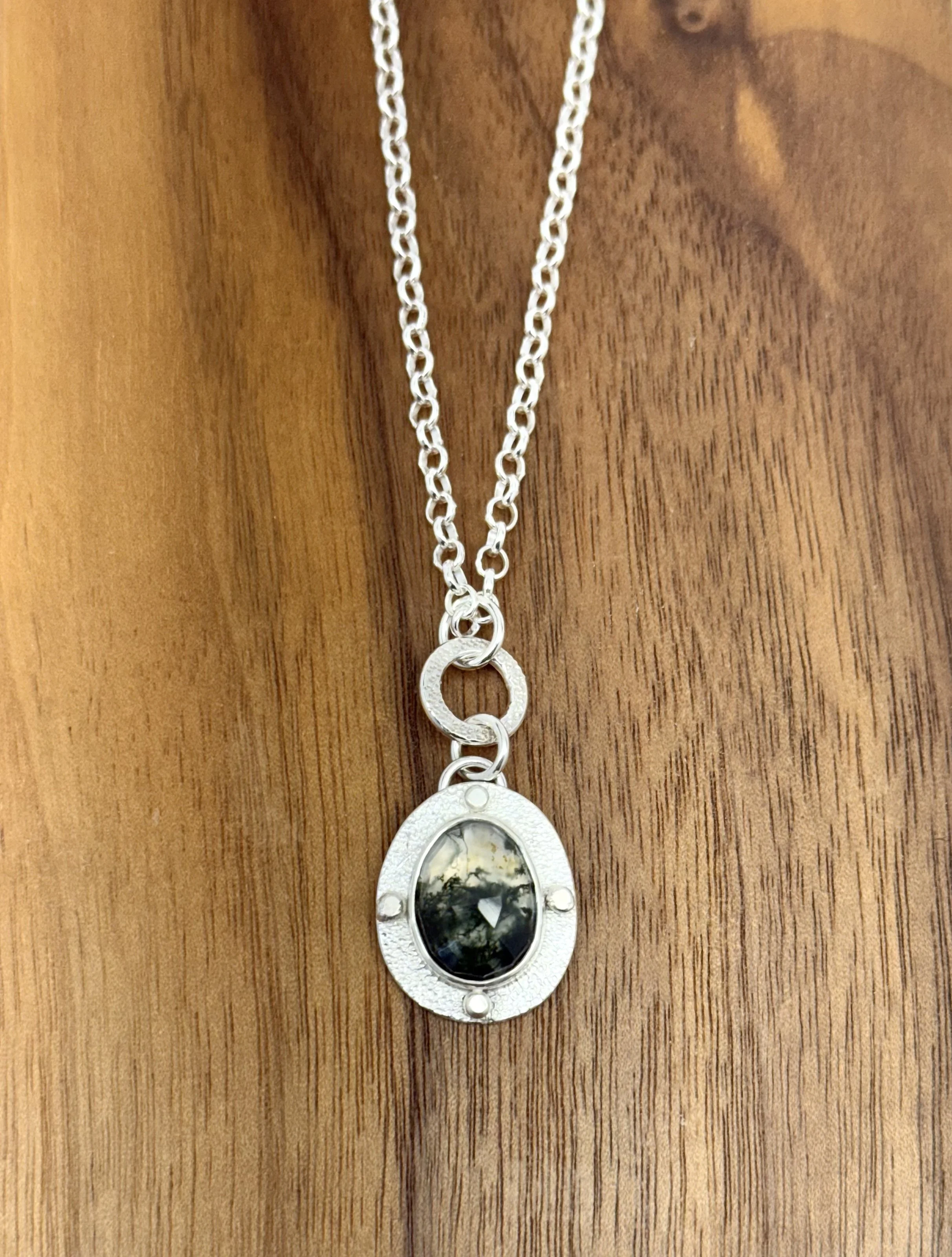 Modern Relic Pendant moss agate lying flat on wood.jpg