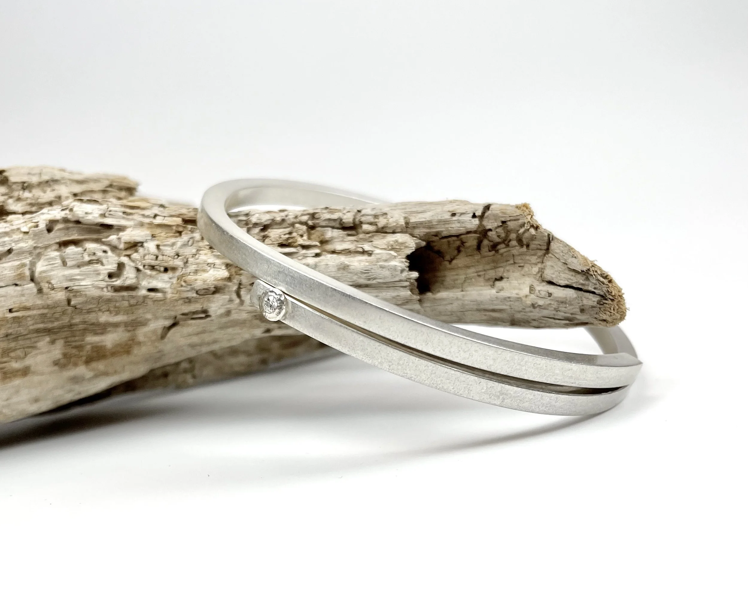 Handcrafted sterling silver Wrapped Bangle bracelet with minimalist modern design, featuring a sleek wrap detail and a moissanite accent.