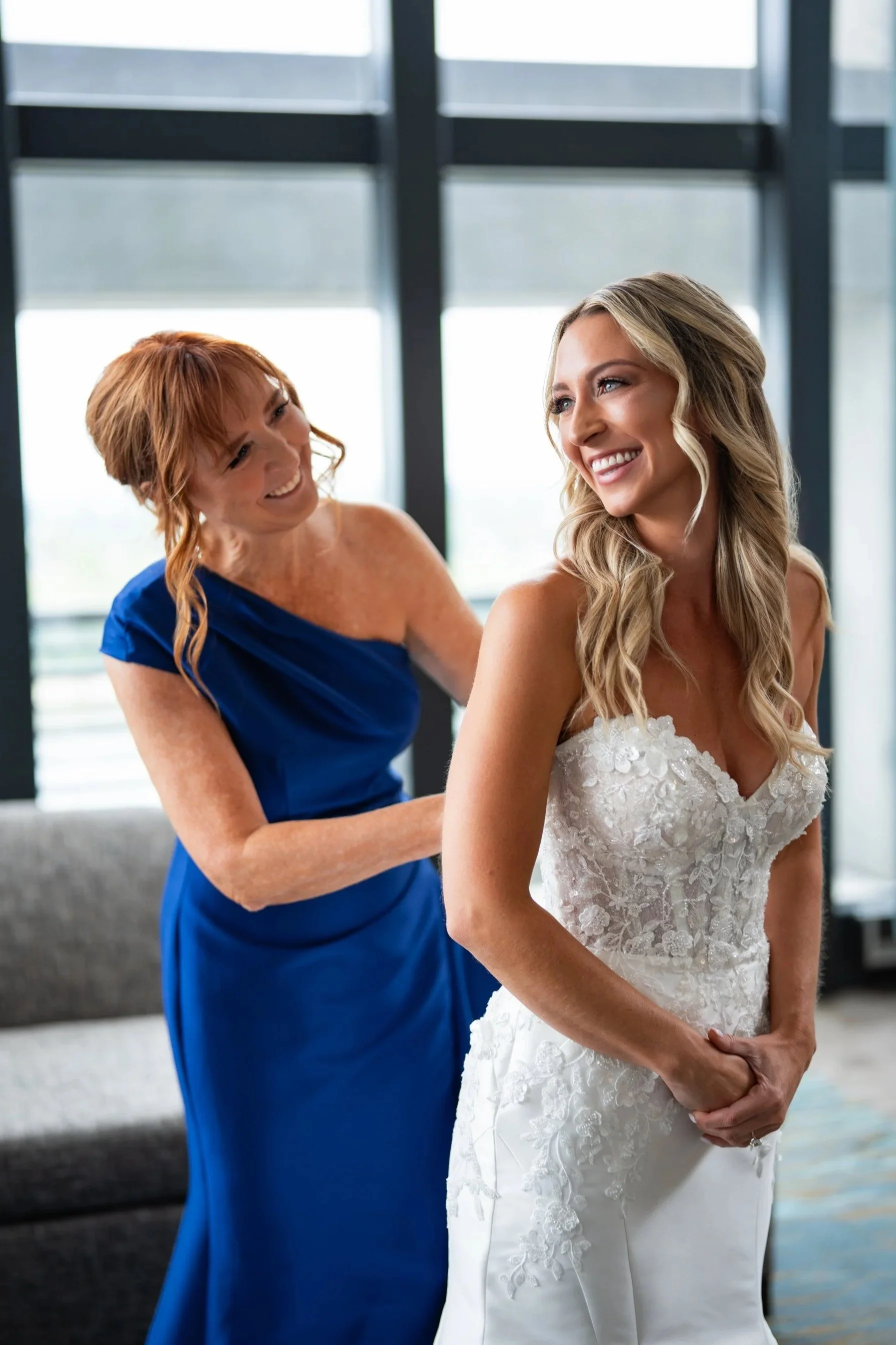 Bride from Zam Wedding, Mother buttoning dress and bride smiling. Captured at Toledo, Ohio Hilton Garden Inn, by Colbis Photo