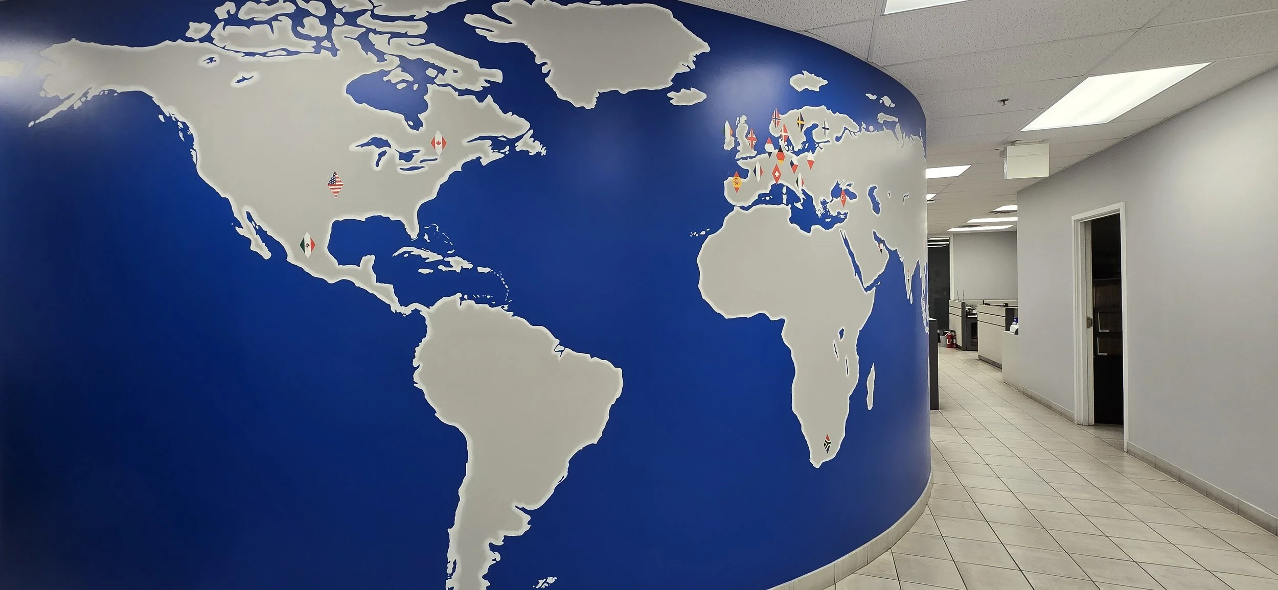 A curved map wall with logo-shaped flags to show off the locations of each global office and corresponding flag