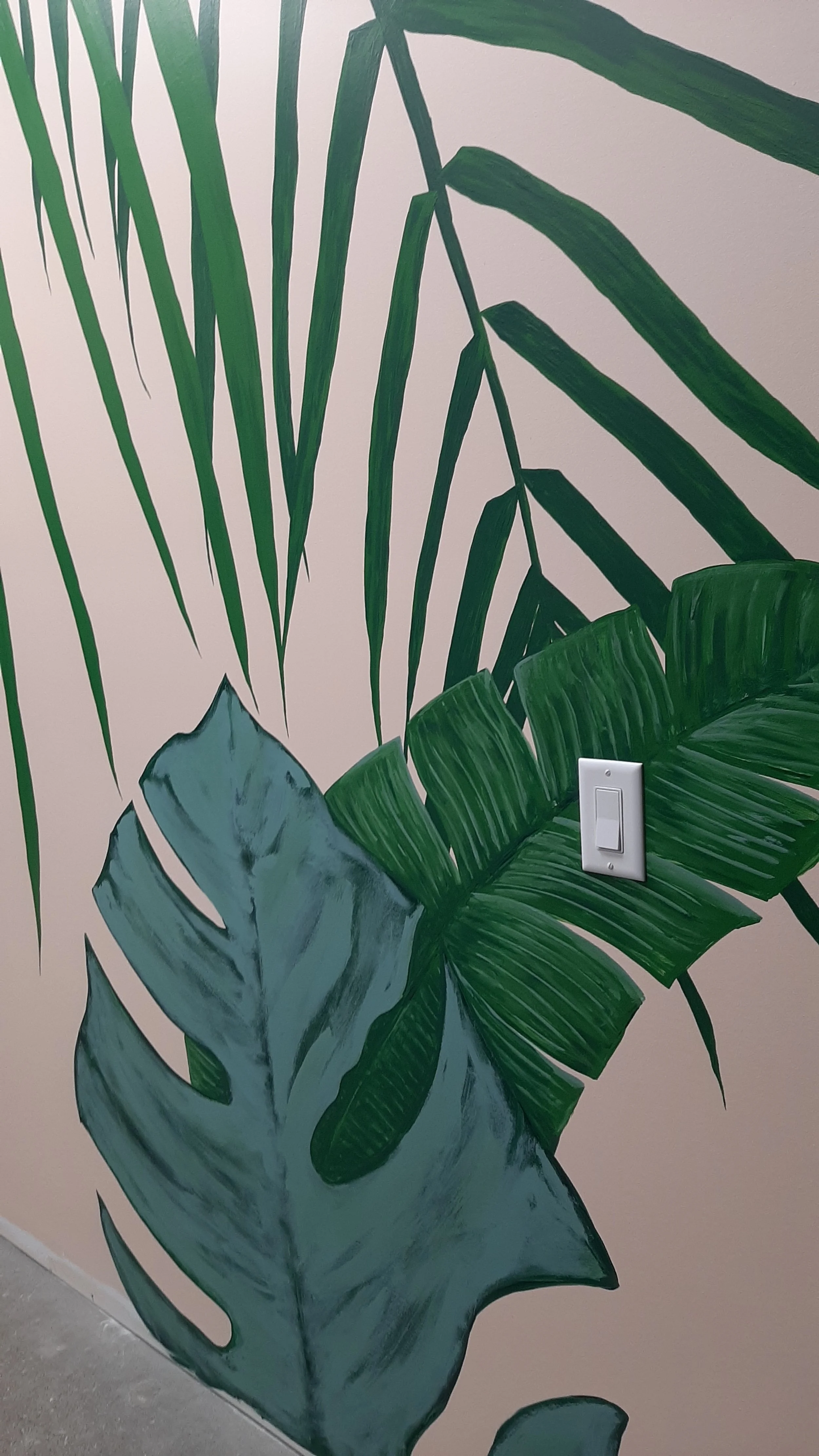 This office got a fresh, playful feel with hand-painted monstera and palm leaves.