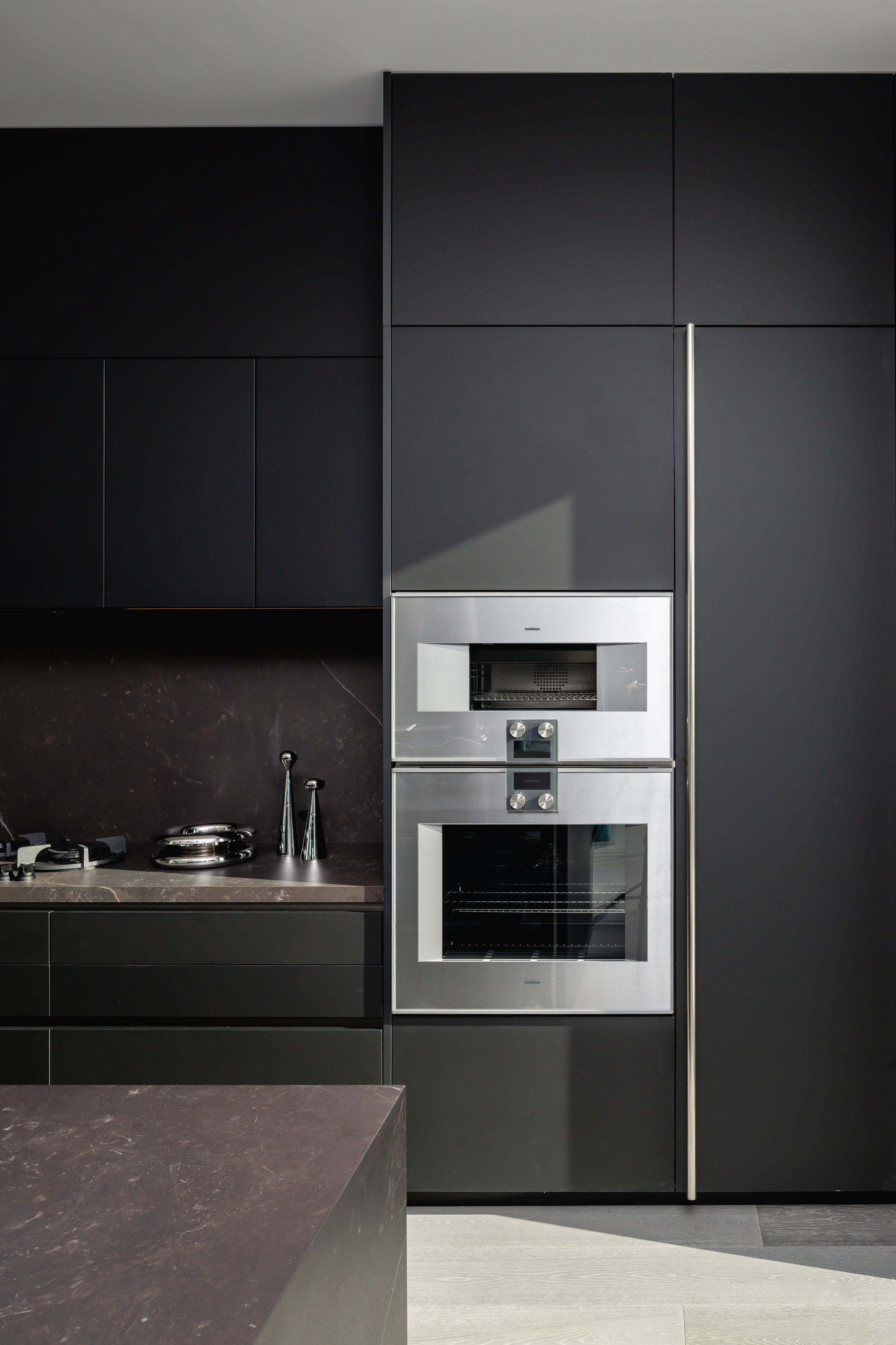 Modern kitchen with black cabinets and stainless steel built-in oven and microwave.