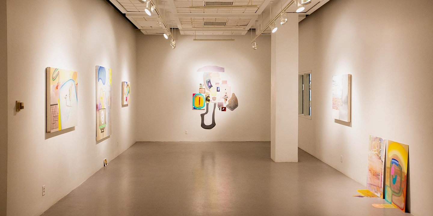 Art gallery with abstract paintings hanging on white walls, spotlights on ceiling, polished gray floor, no visitors.