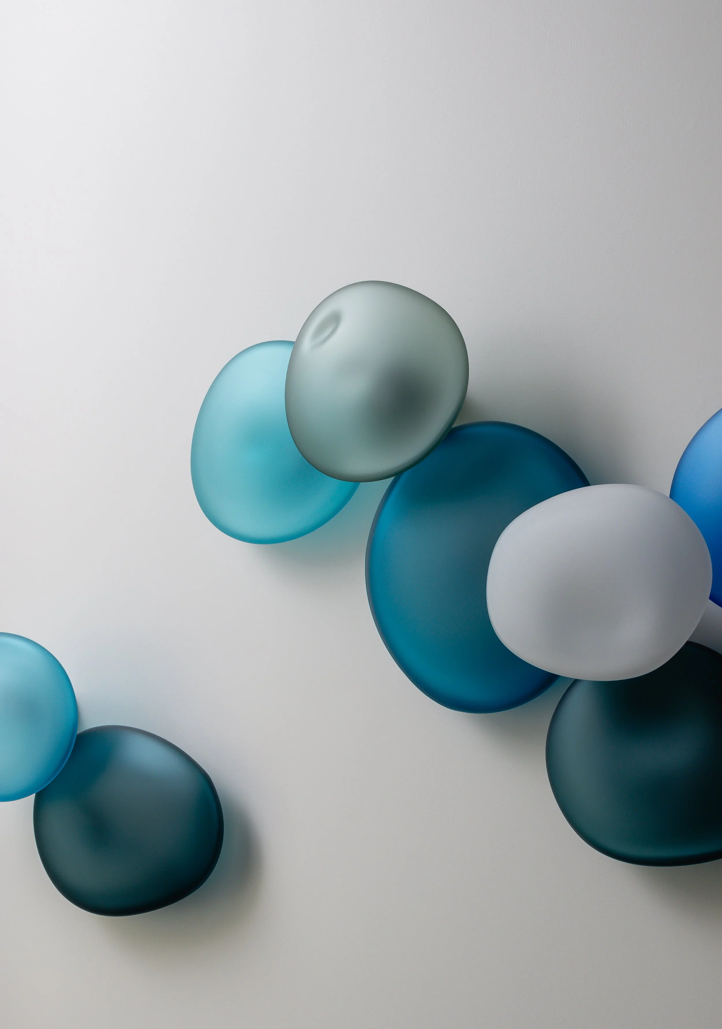 A collection of semi-transparent balloons in shades of blue, gray, and white arranged on a white surface.