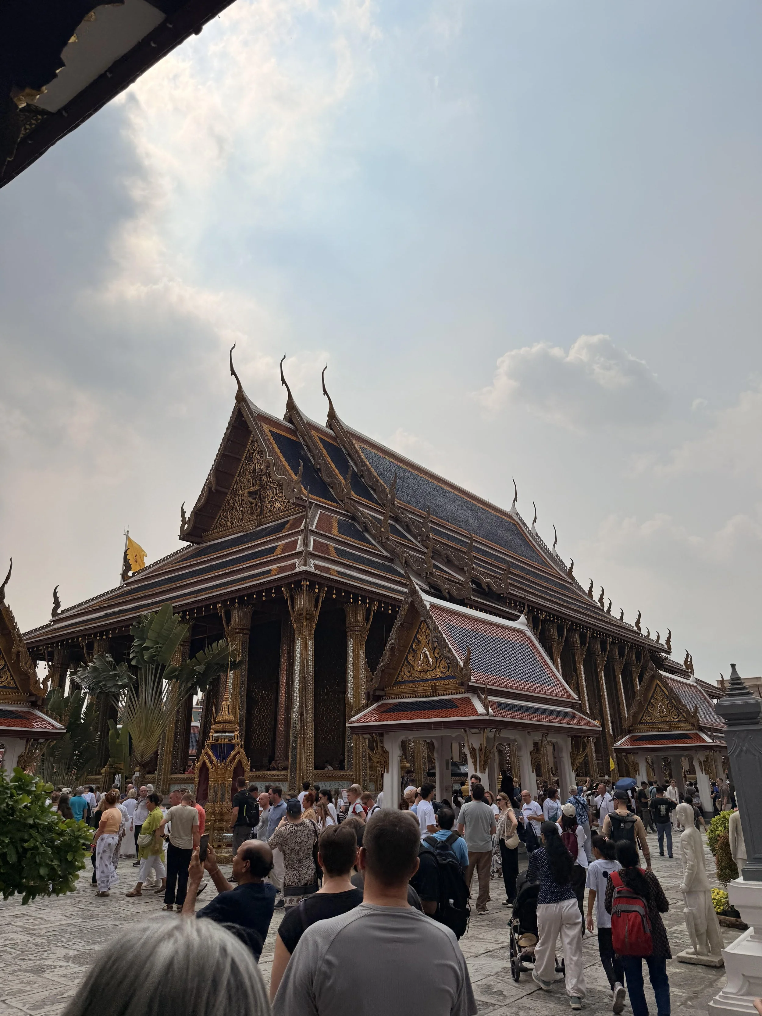 People visiting a traditional Thai temple with ornate roofs and detailed decorations.