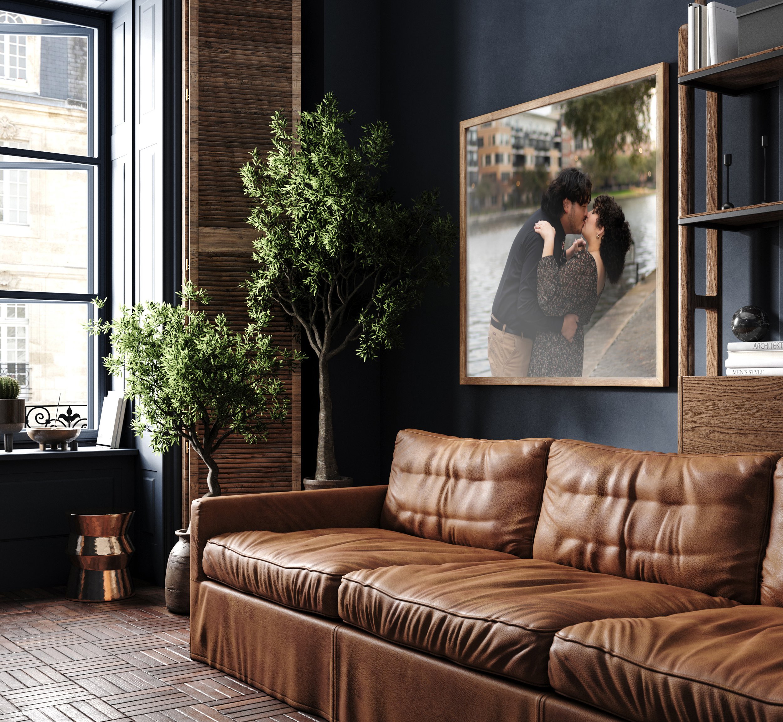 Modern living room with brown leather sofa, framed romantic photo, indoor plants, large windows.