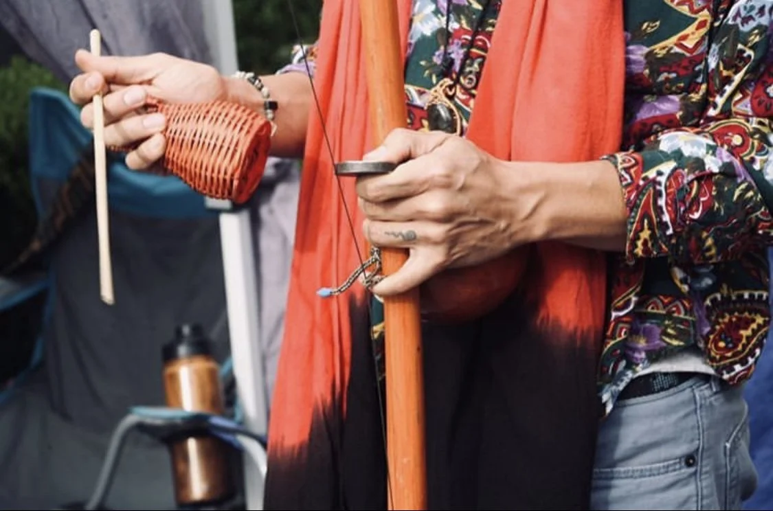 Close-up of Capoeira de Angola instructor Nico Zuluaga's hands playing a berimbau, a traditional capoeira instrument. 