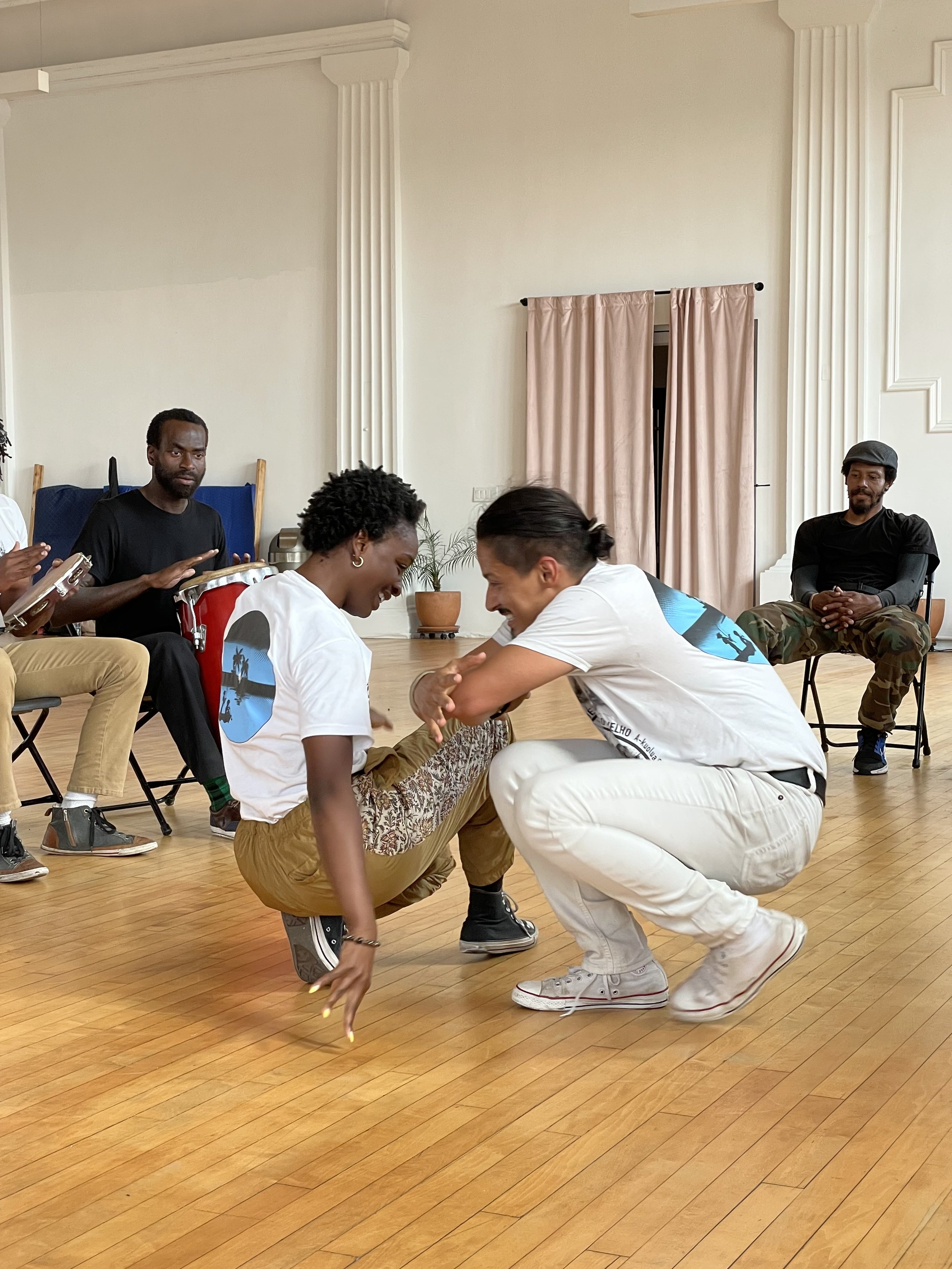 Capoeira de Angola instructor Nico Zuluaga and student of N'gola Preto Velho engage in a capoeira training session.
