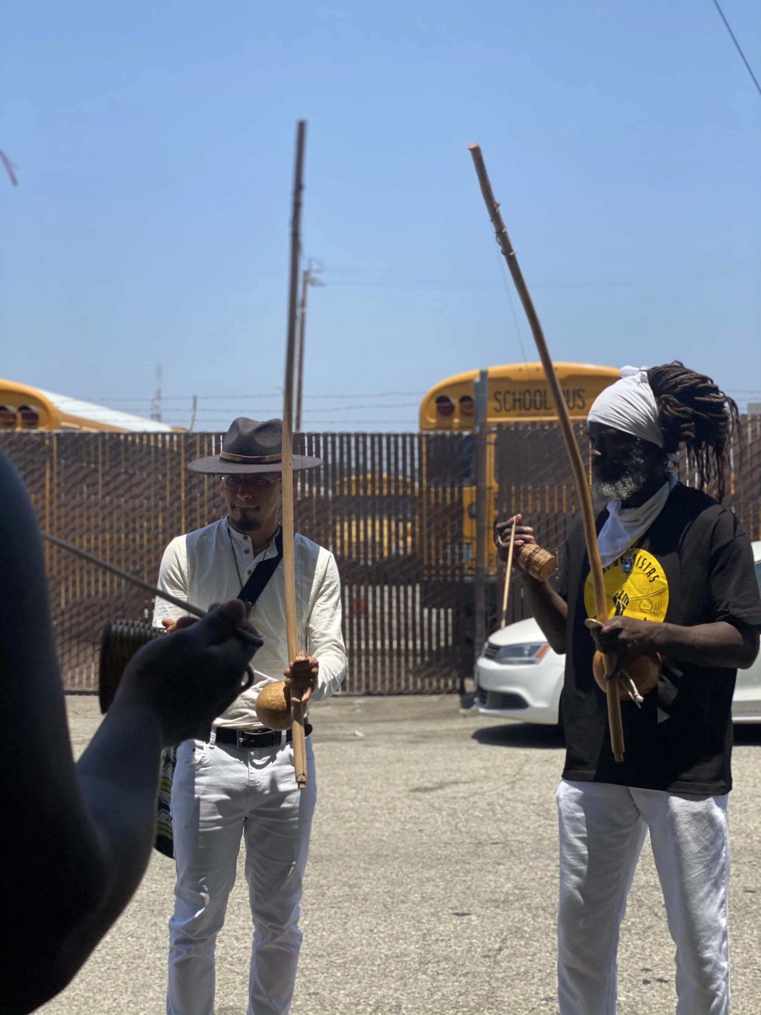 Capoeira de Angola instructor Nico Zuluaga and Treinel Mo of N'gola Preto Velho play berimbau in downtown Los Angeles during a community march and demonstration. 