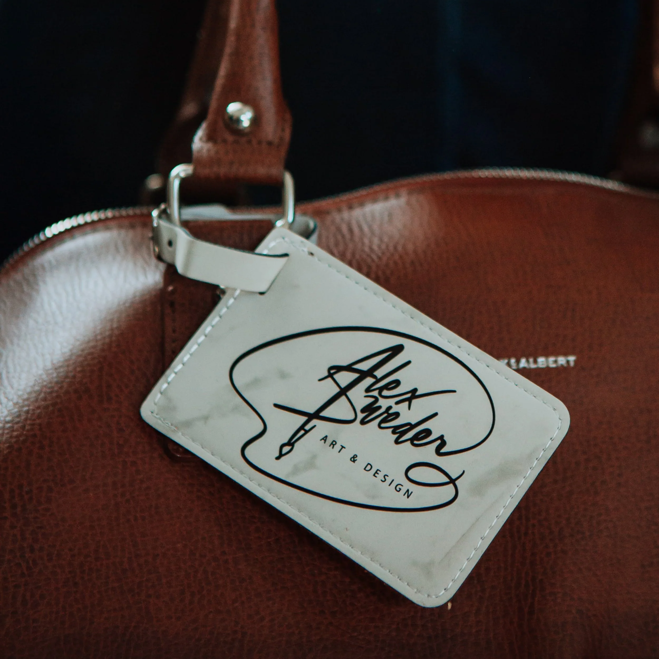 Several blue leather luggage tags with white text reading 'BOLD CO MOVES &' stacked on a rustic surface.