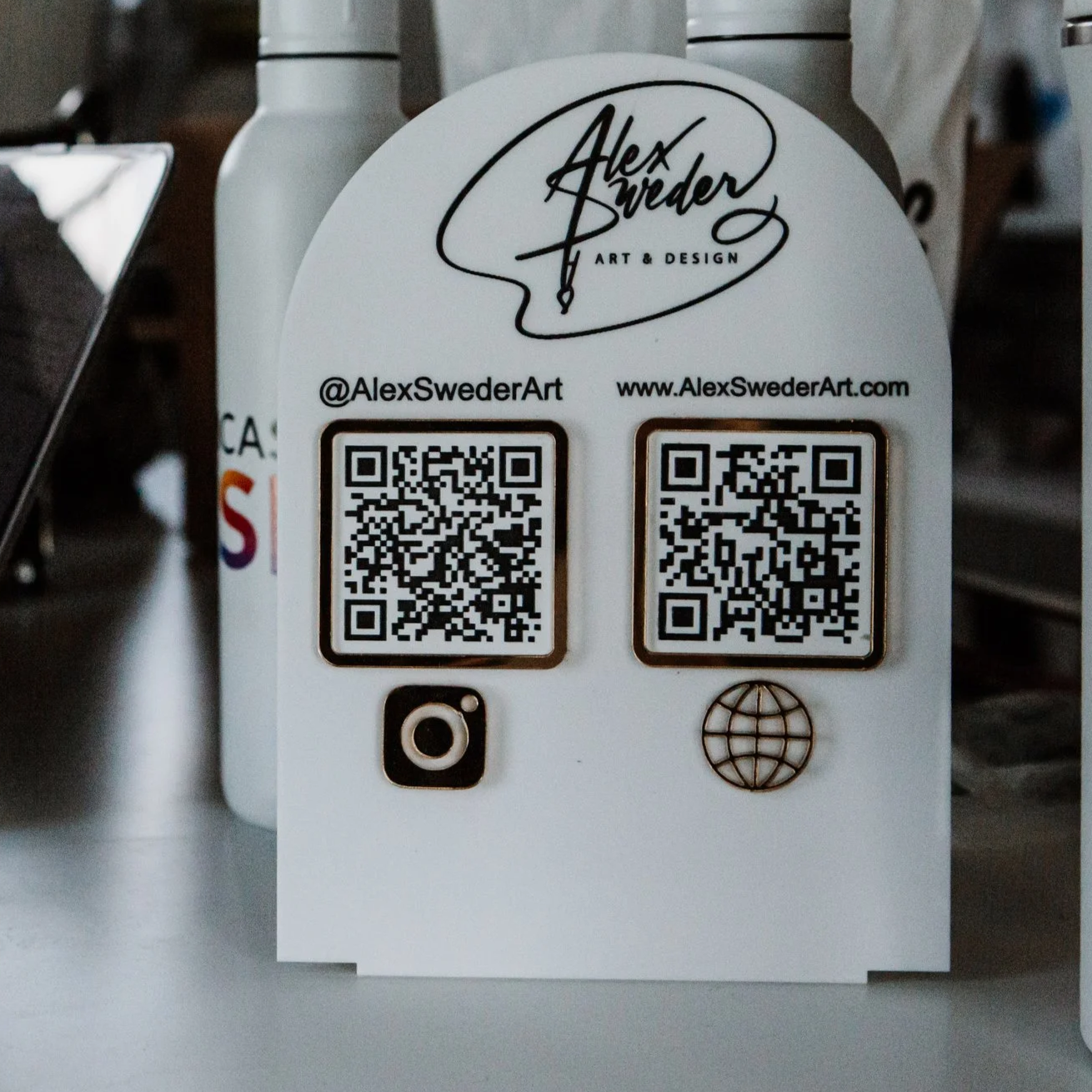 A display promoting ear piercing by Nurse Cassandra, with options to tap or scan for service, featuring a logo of a woman's profile with a hairstyle, and a small accessory with the same logo.