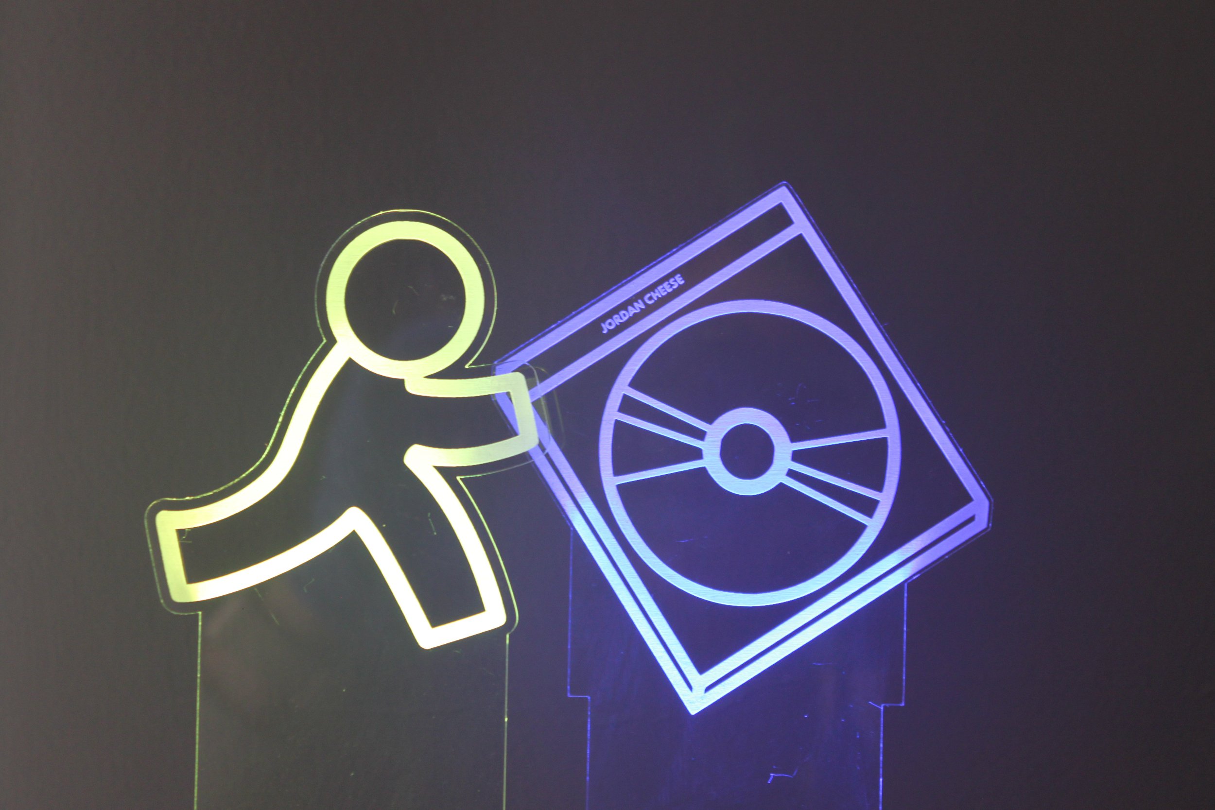 Neon sign of a stick figure carrying a cheese wheel labeled 'Jordan Cheese'.