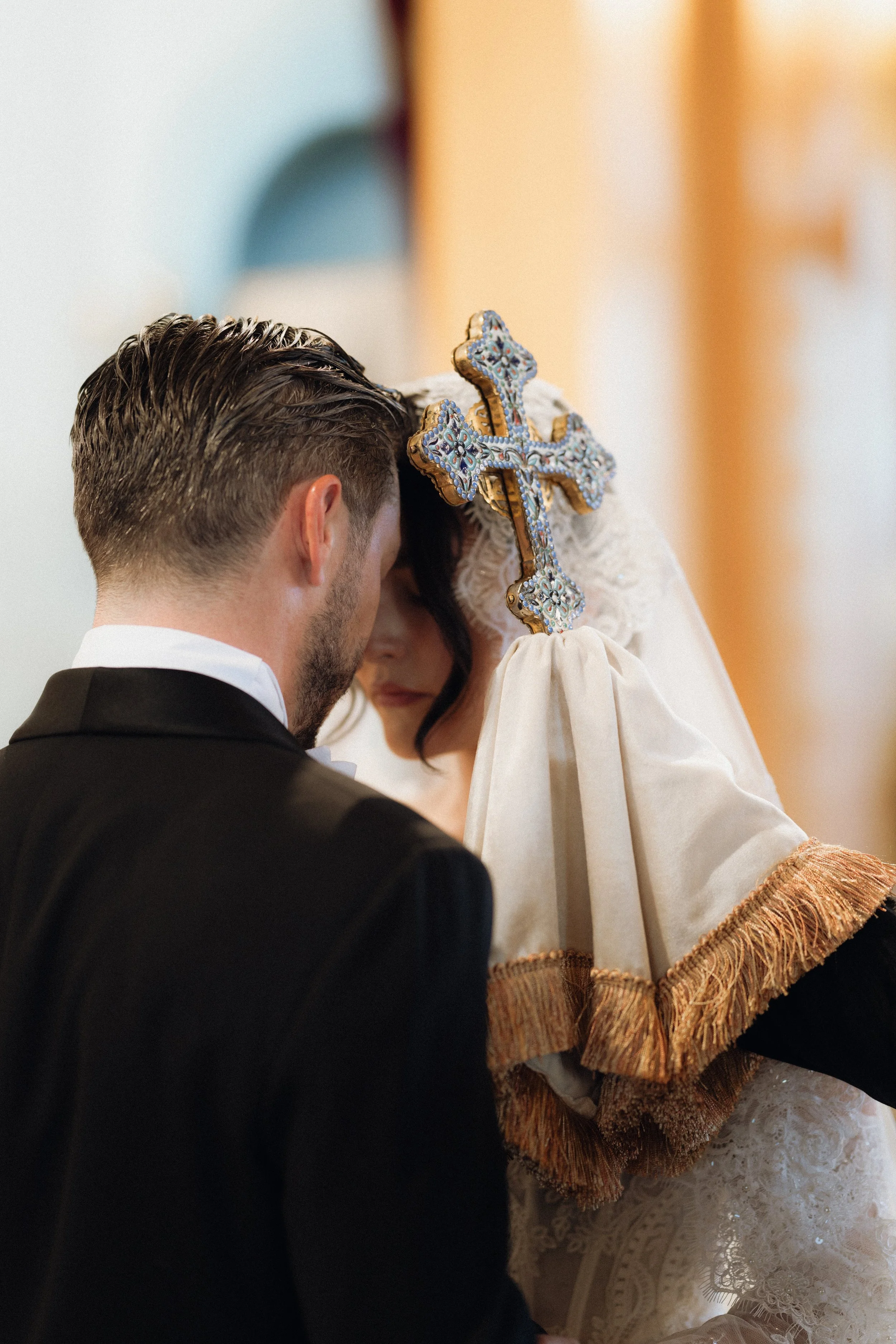 A groom and bride during their wedding ceremony, standing close together with heads bowed.