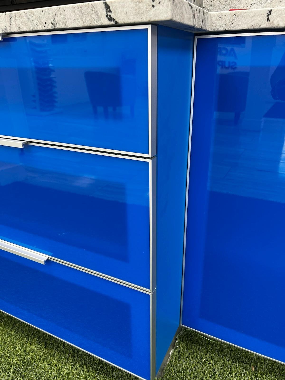 Close-up of blue acrilic kitchen cabinets with a granite countertop. PVC cabinets