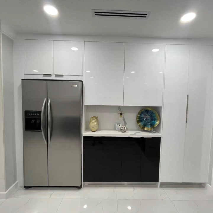 Modern kitchen with stainless steel refrigerator, white cabinets, decorative owl figurines, and a colorful blue and green plate on display.