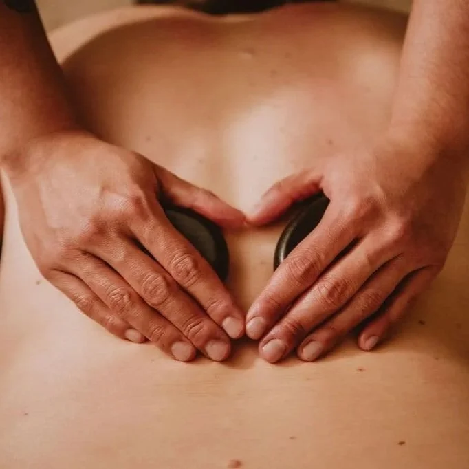 licensed massage therapists using hands and hot stones to help a client with their low back pain at The Studios at Summit