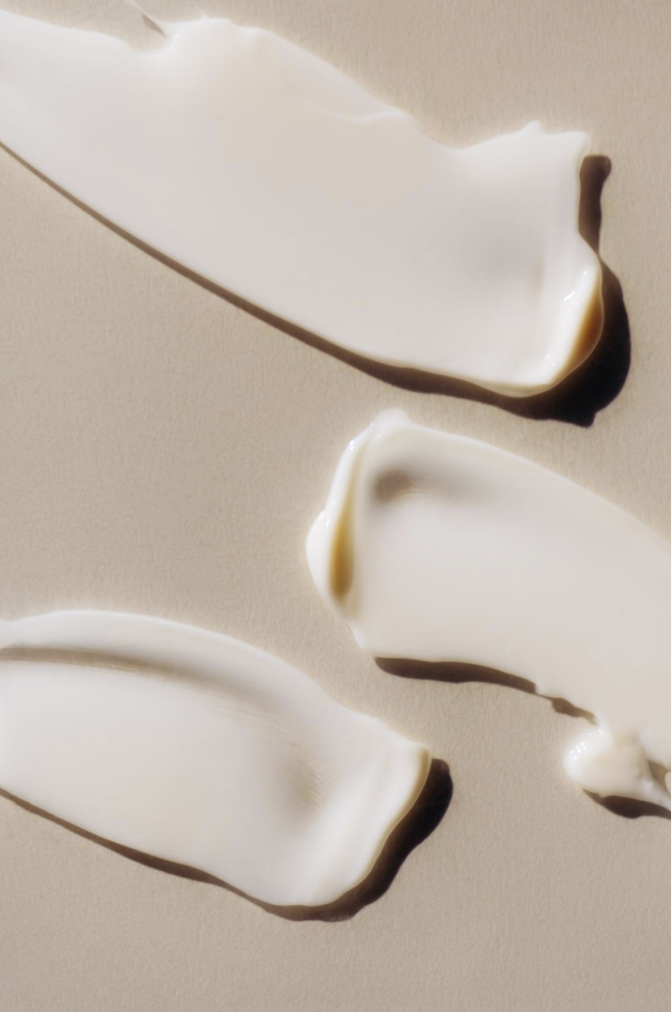 Three streaks of white cream with dark chocolate edges on a beige surface.