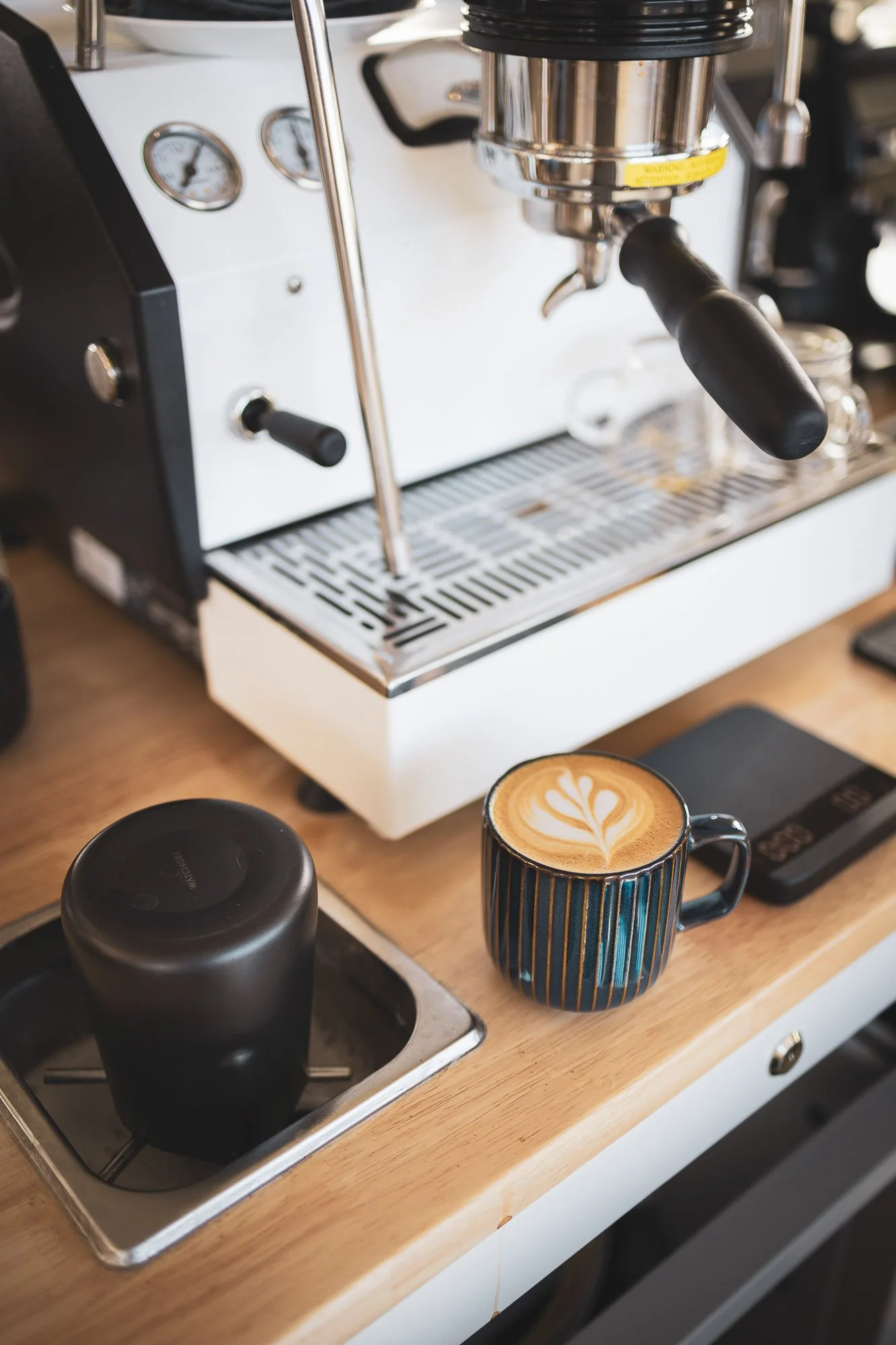 Close-up of a coffee machine on a kitchen counter with a mug of latte art in front.