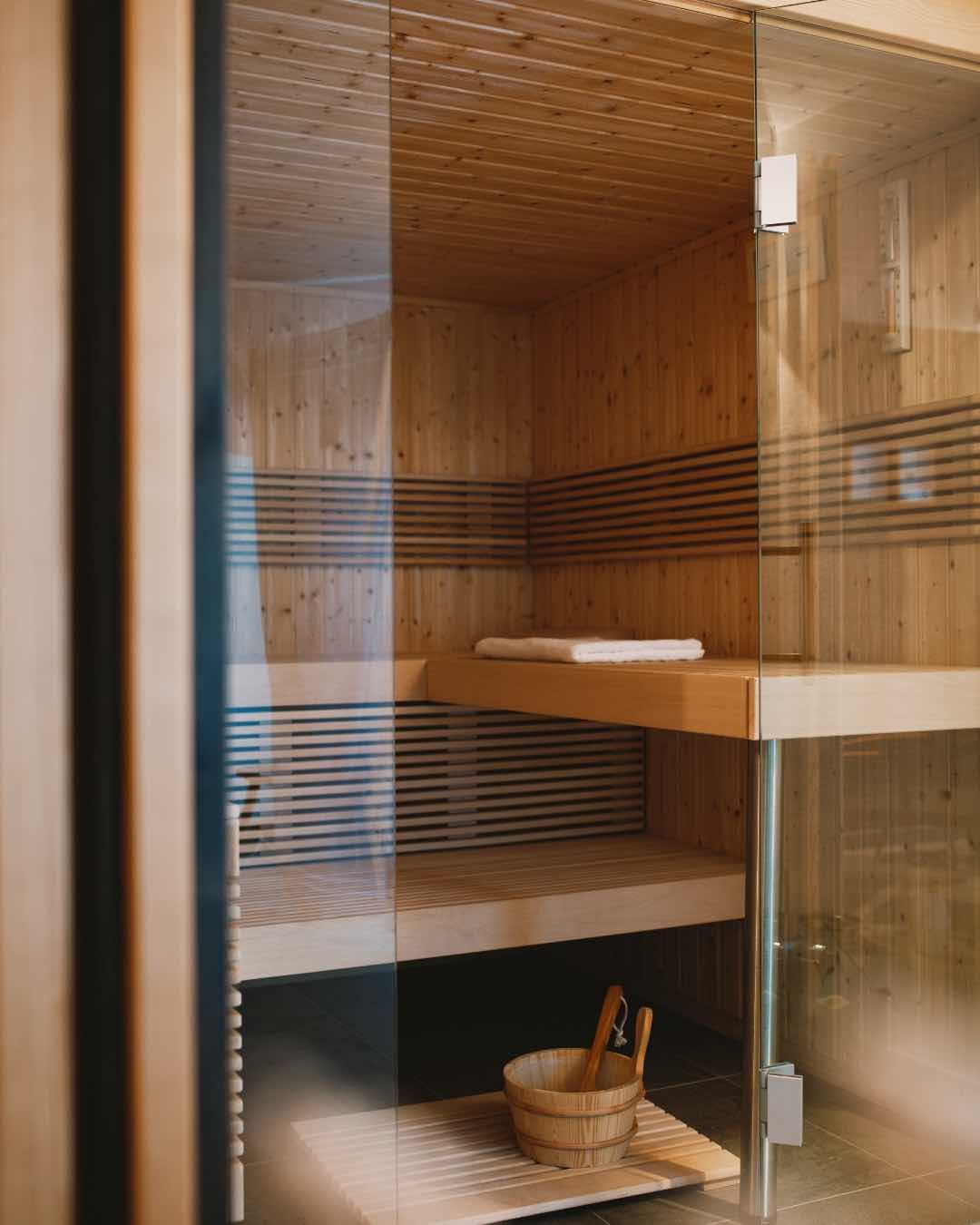 Innenansicht einer Holzhütte mit Sauna, Holzsitze, Handtücher und ein Holzbadewannen-Set